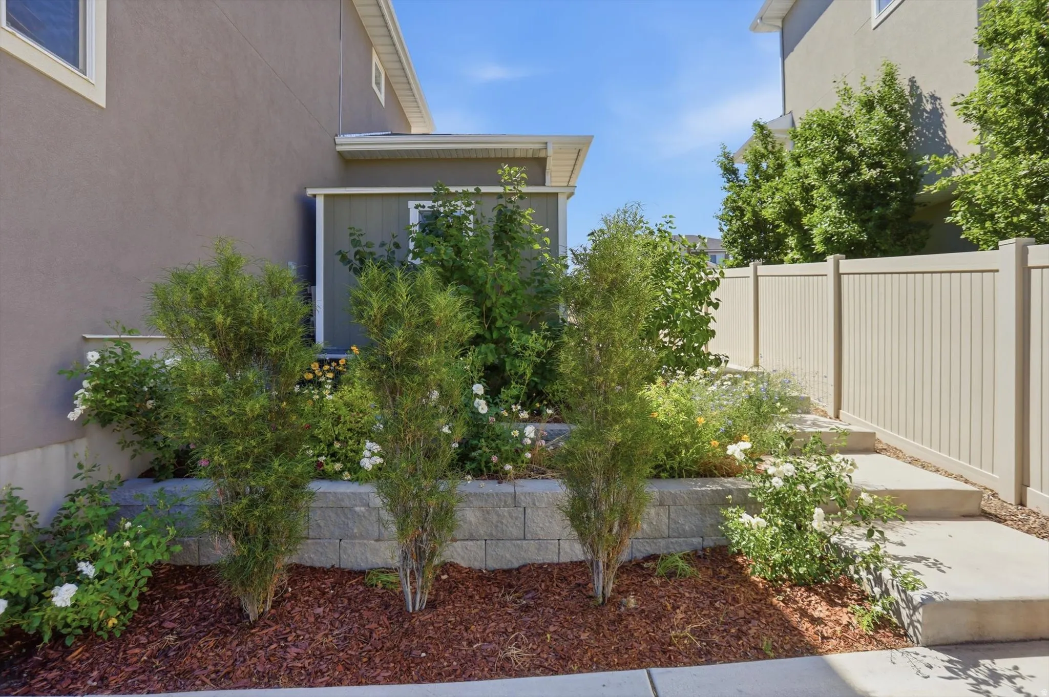 Tiered landscaping with a retaining wall, mature shrubbery, and a concrete pathway