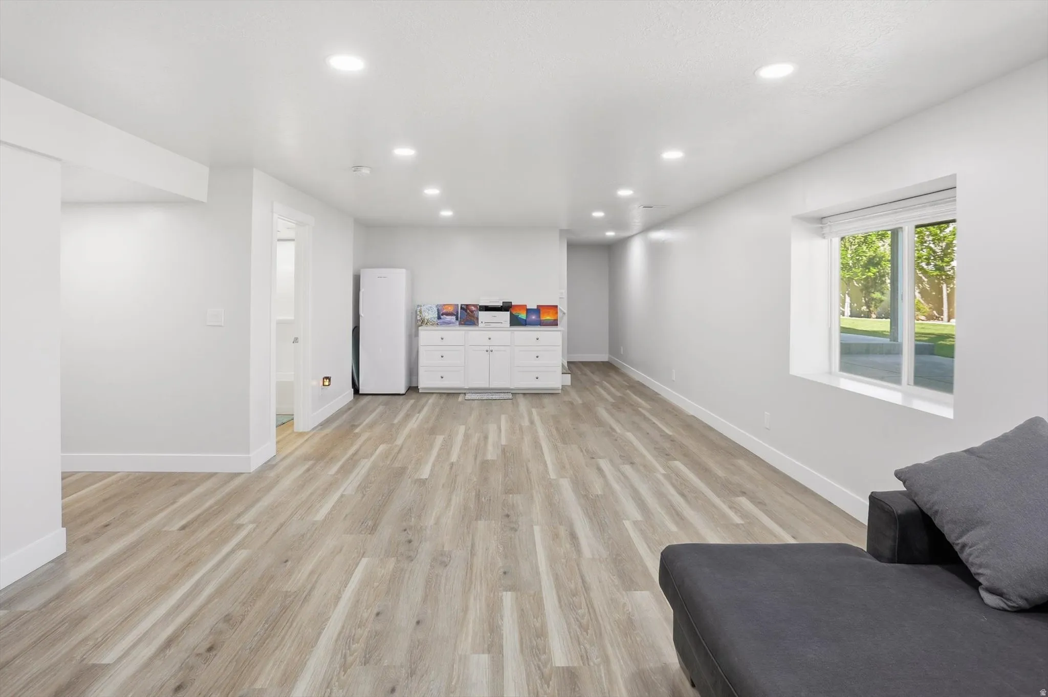 Spacious room featuring wood-finish flooring, recessed lighting, and a window with exterior views