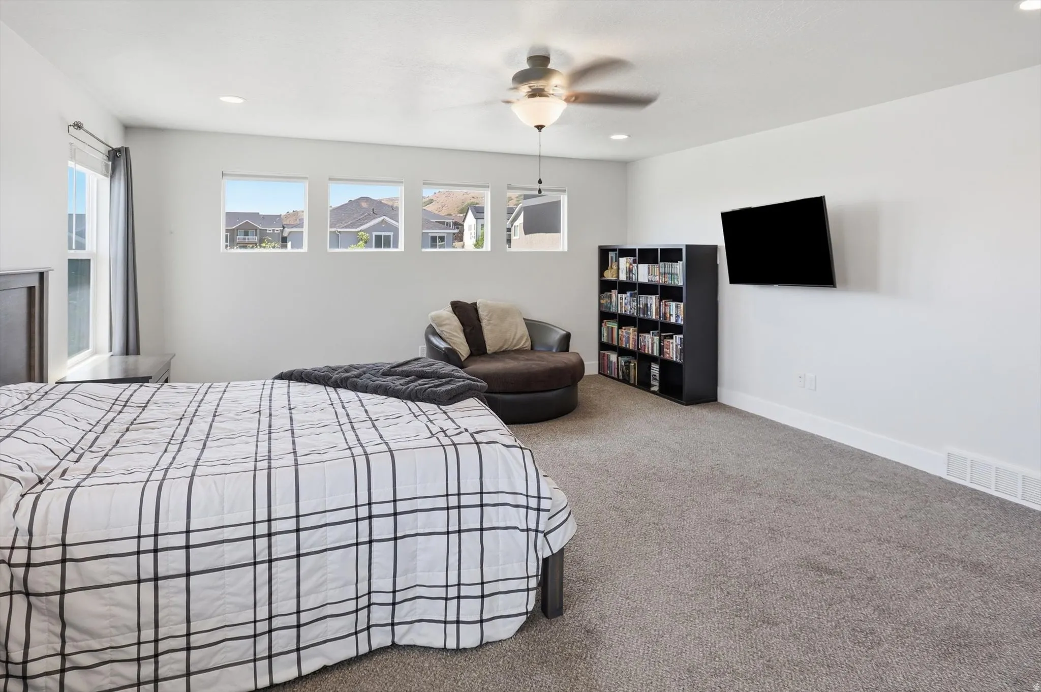 Carpeted room featuring multiple windows, recessed lighting, and a ceiling fan with integrated light