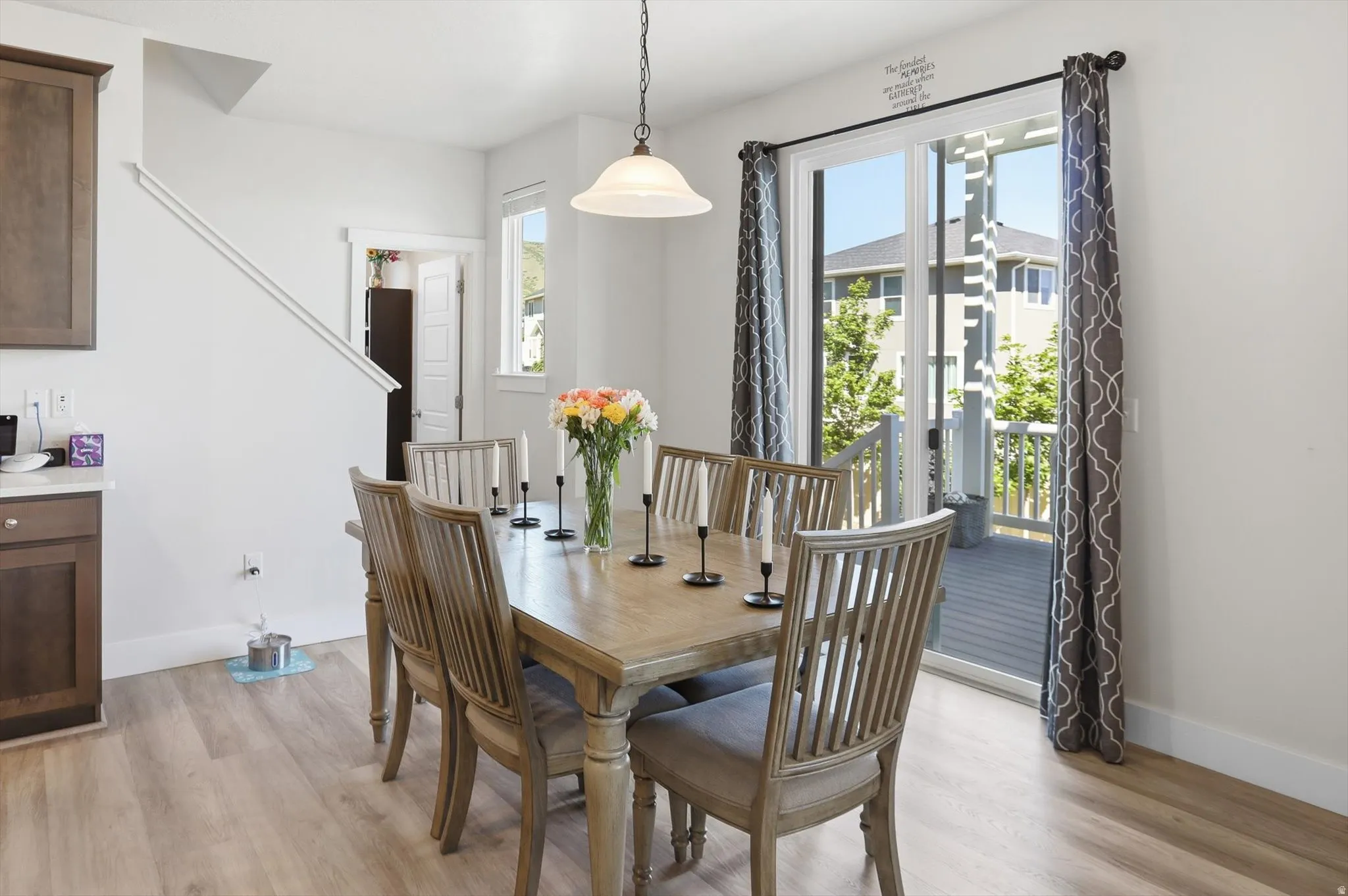 Dining area featuring wood-finish flooring, a sliding glass door providing access to an outdoor deck, and a contemporary pendant light fixture