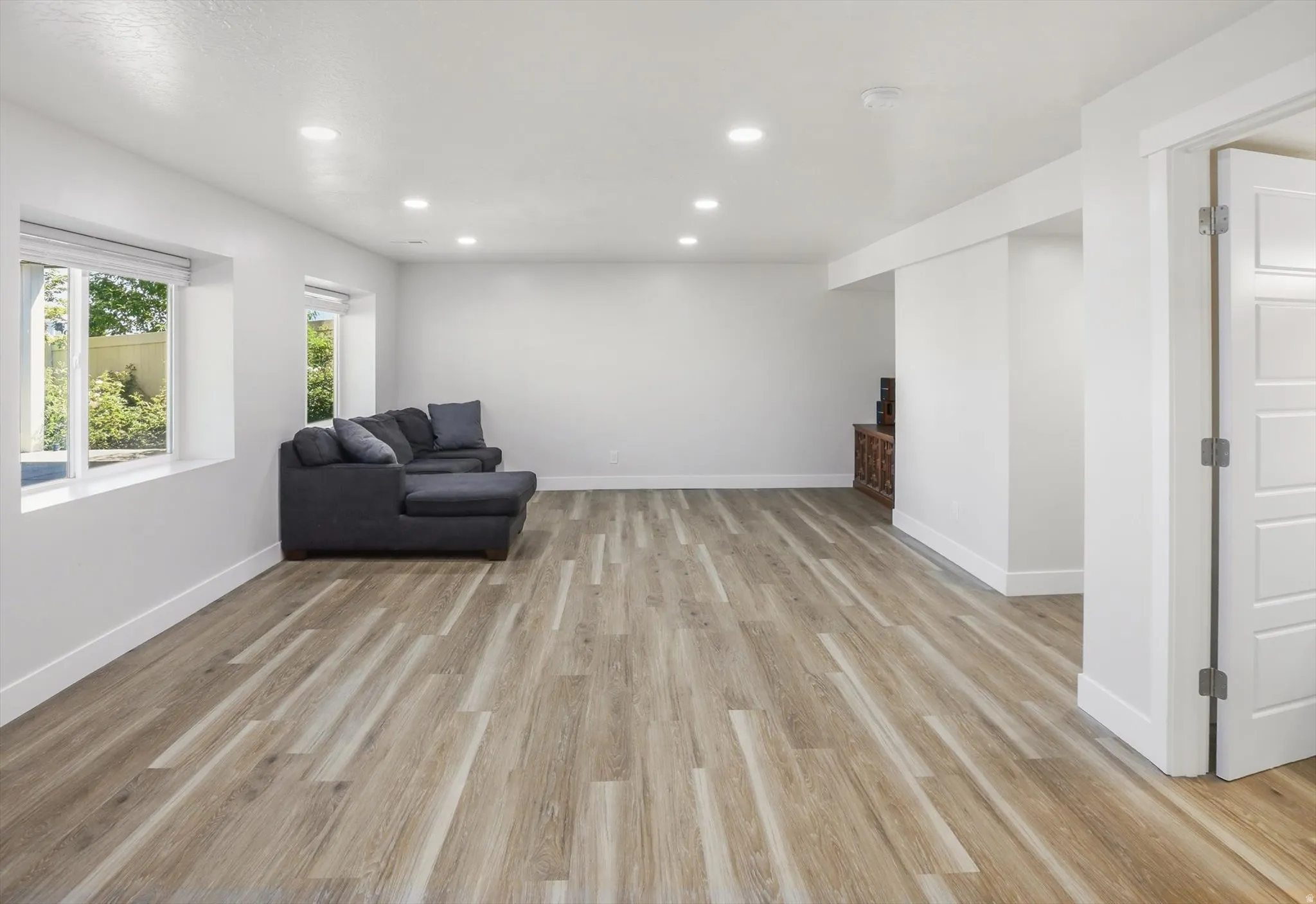 Spacious room featuring wood-finish flooring, recessed lighting, and large windows