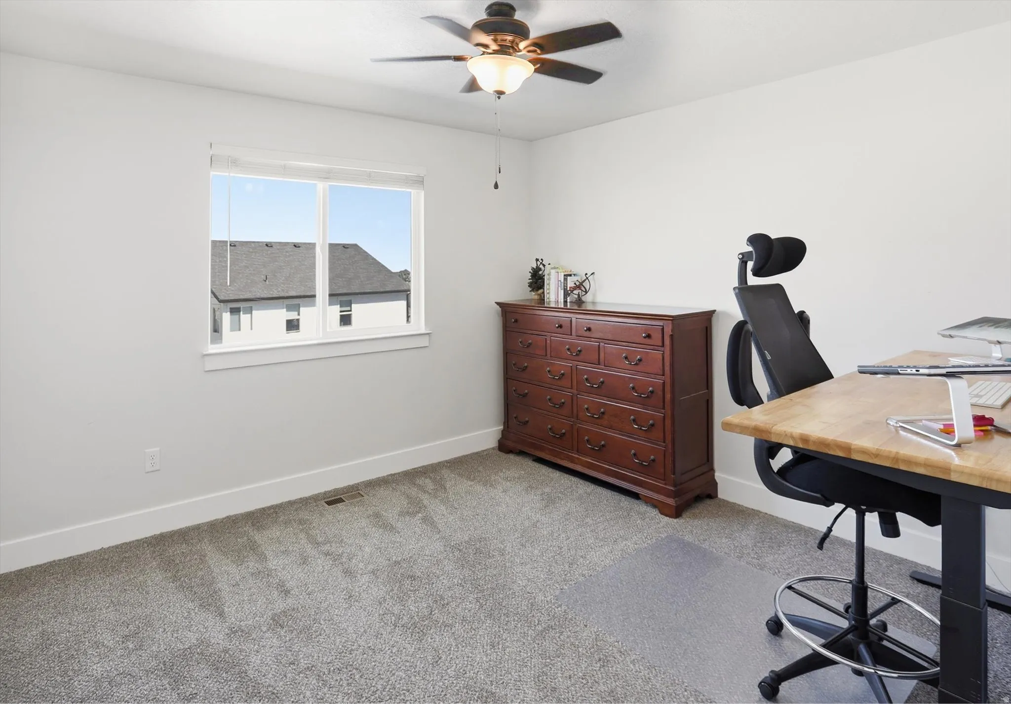 Room featuring neutral-toned carpet, white walls, and a ceiling fan with integrated lighting