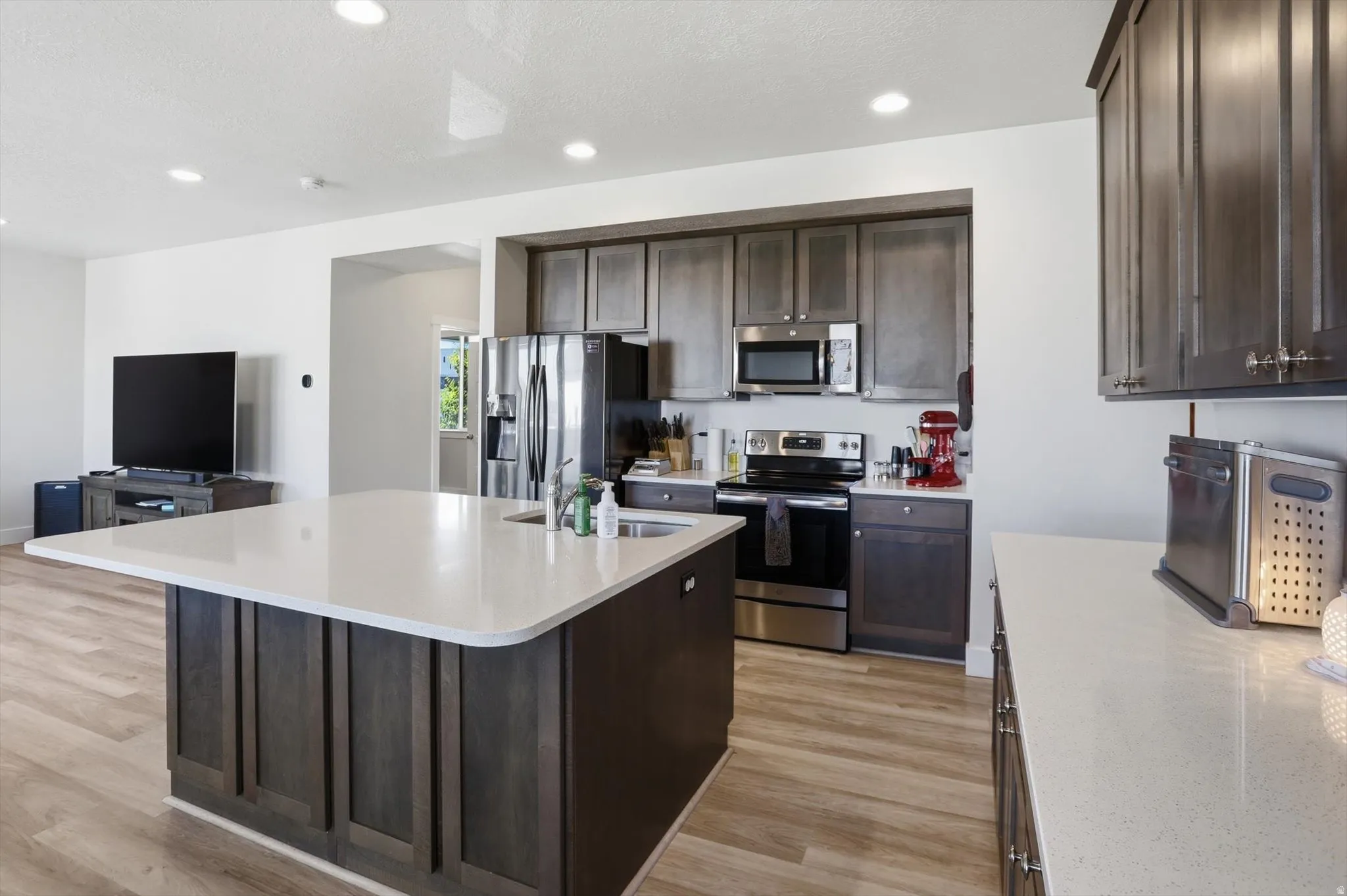 Kitchen featuring dark wood-finish cabinetry, stainless steel appliances, and light-toned countertops