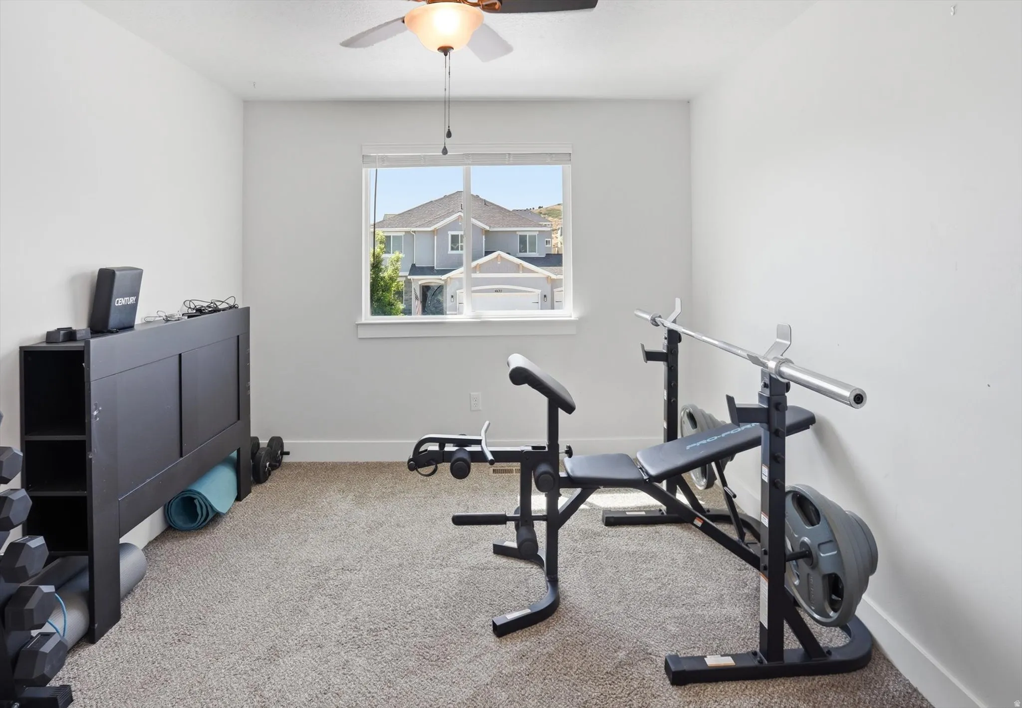 Carpeted room featuring a ceiling fan with integrated lighting, a window with white trim, and white walls