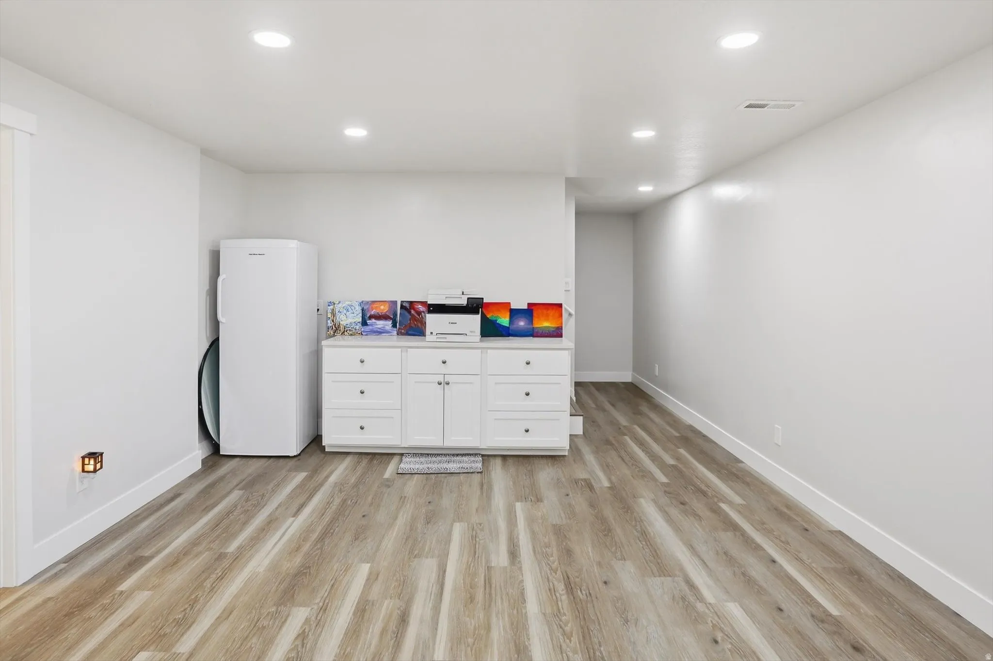 Open room featuring wood-finish flooring, recessed ceiling lighting, and crisp white walls