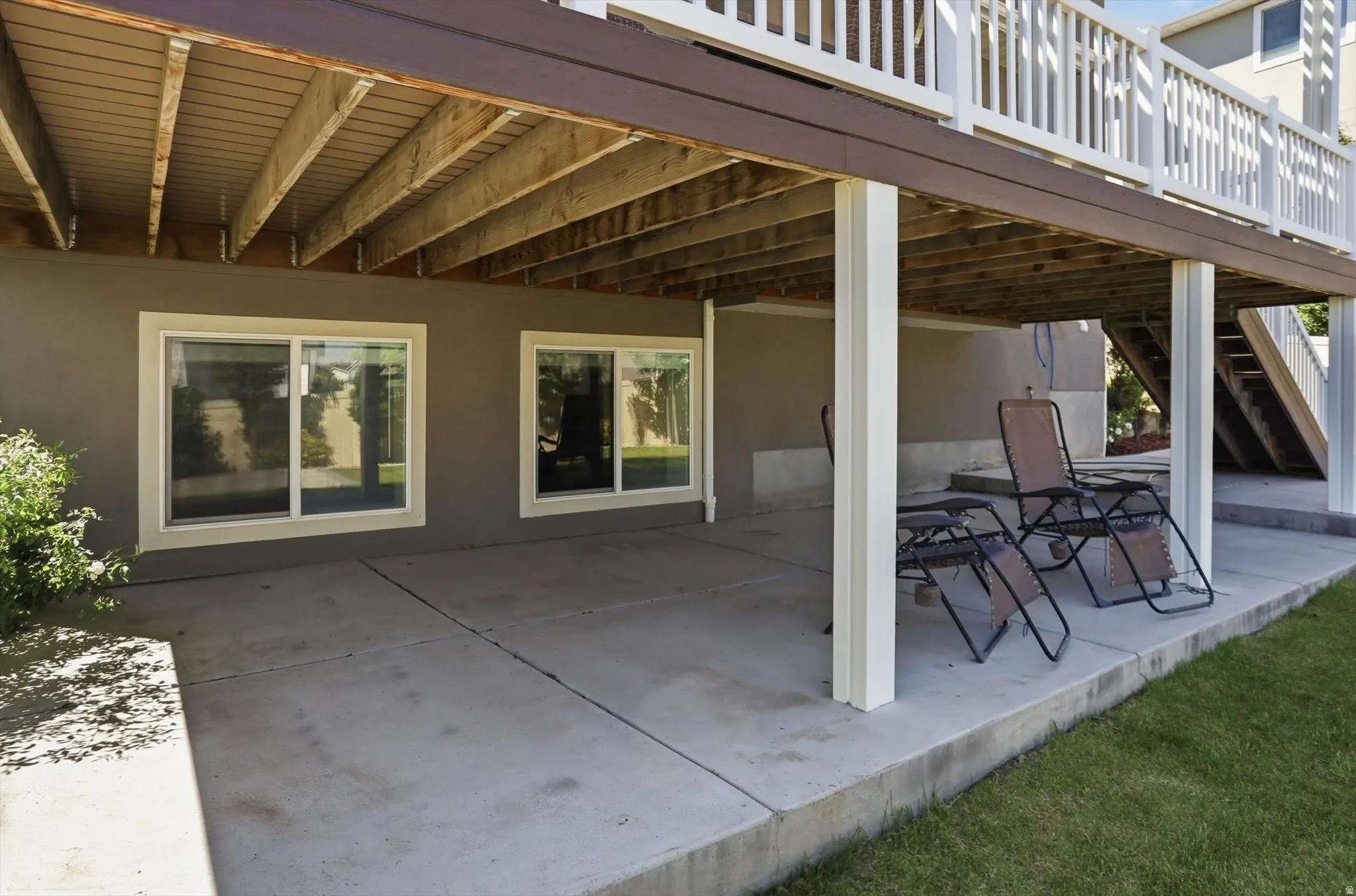 Covered concrete patio with a finished under-deck ceiling, supported by white columns