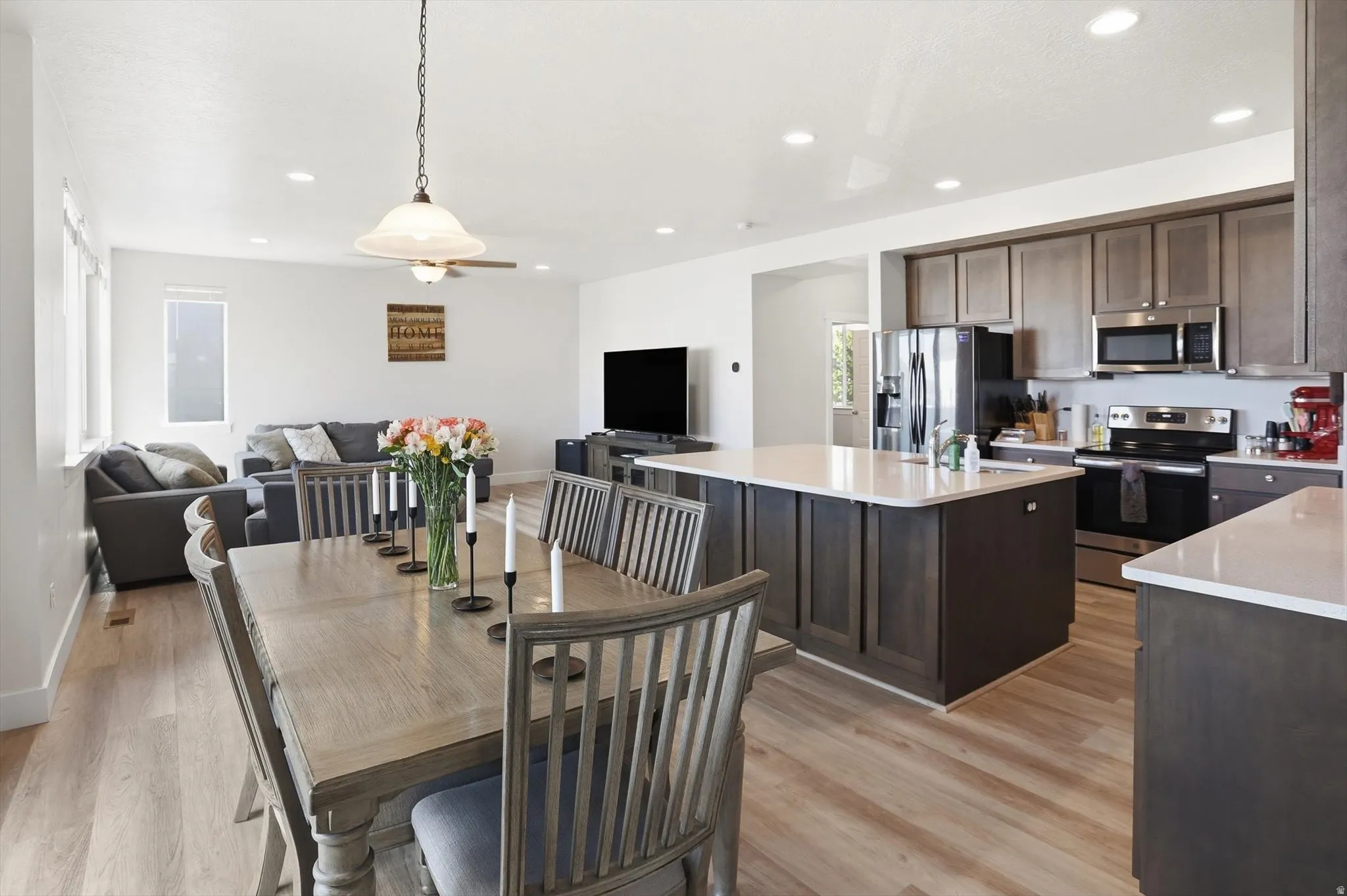Open-concept living space featuring wood-finish flooring, recessed lighting, and a contemporary kitchen with a center island