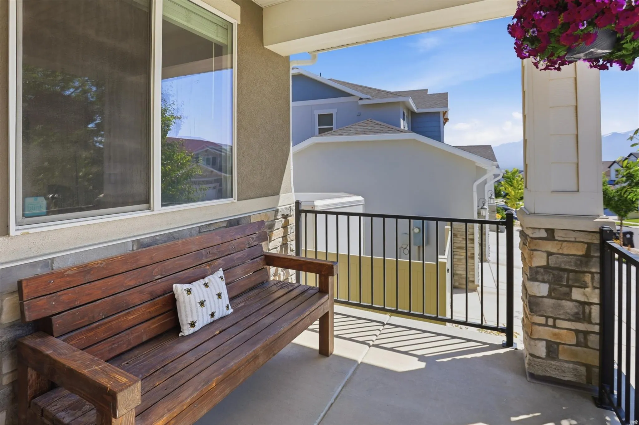 Covered porch featuring a stone and stucco exterior, white framed windows, and black metal railing