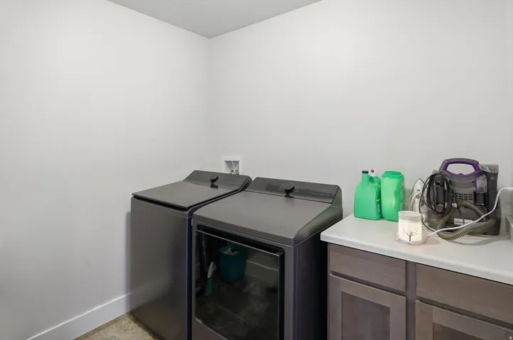 Laundry area featuring light-toned walls, a white baseboard, and a built-in cabinetry unit with a light-colored countertop