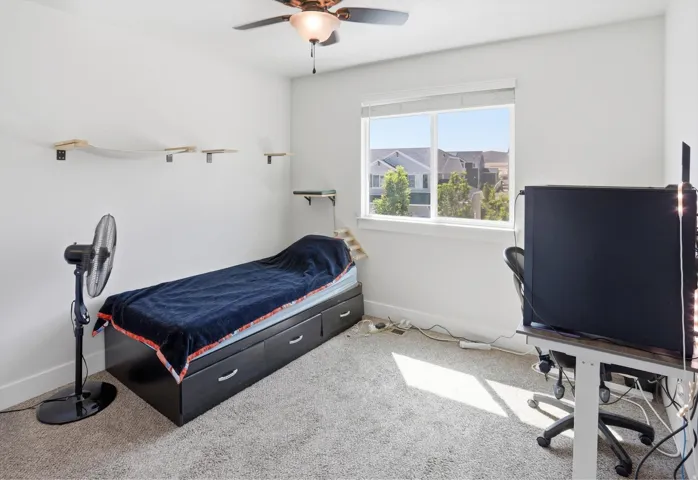 Bright room featuring a ceiling fan, a window with exterior views, and neutral-toned carpeting