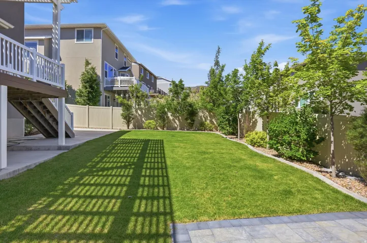 Expansive green lawn with mature trees and shrubs lining the perimeter