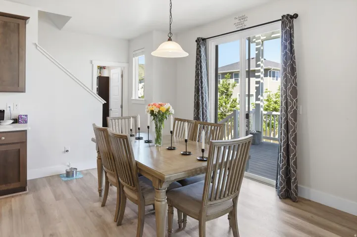 Dining area featuring wood-finish flooring, a sliding glass door providing access to an outdoor deck, and a contemporary pendant light fixture