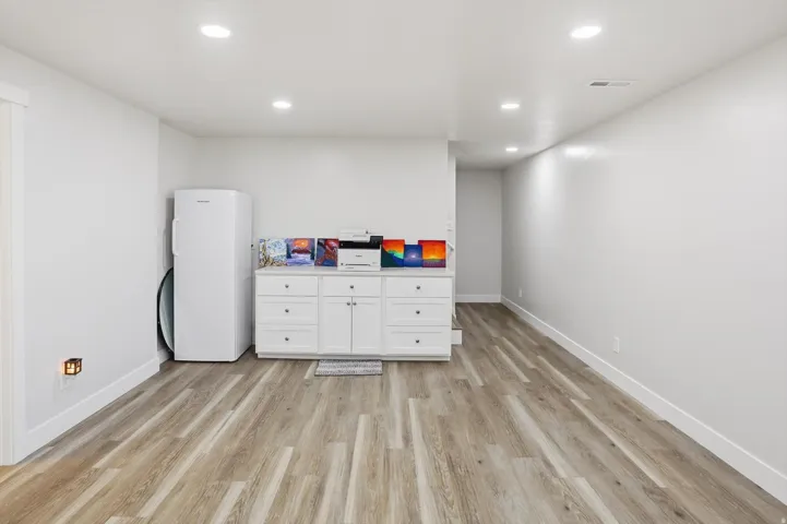 Open room featuring wood-finish flooring, recessed ceiling lighting, and crisp white walls
