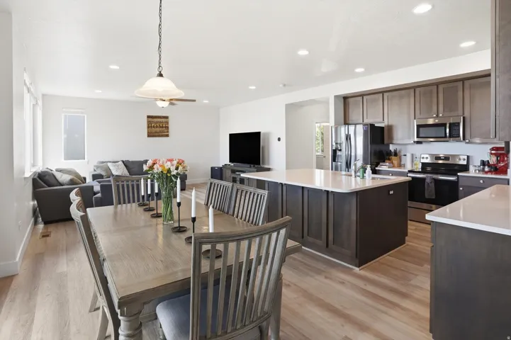 Open-concept living space featuring wood-finish flooring, recessed lighting, and a contemporary kitchen with a center island