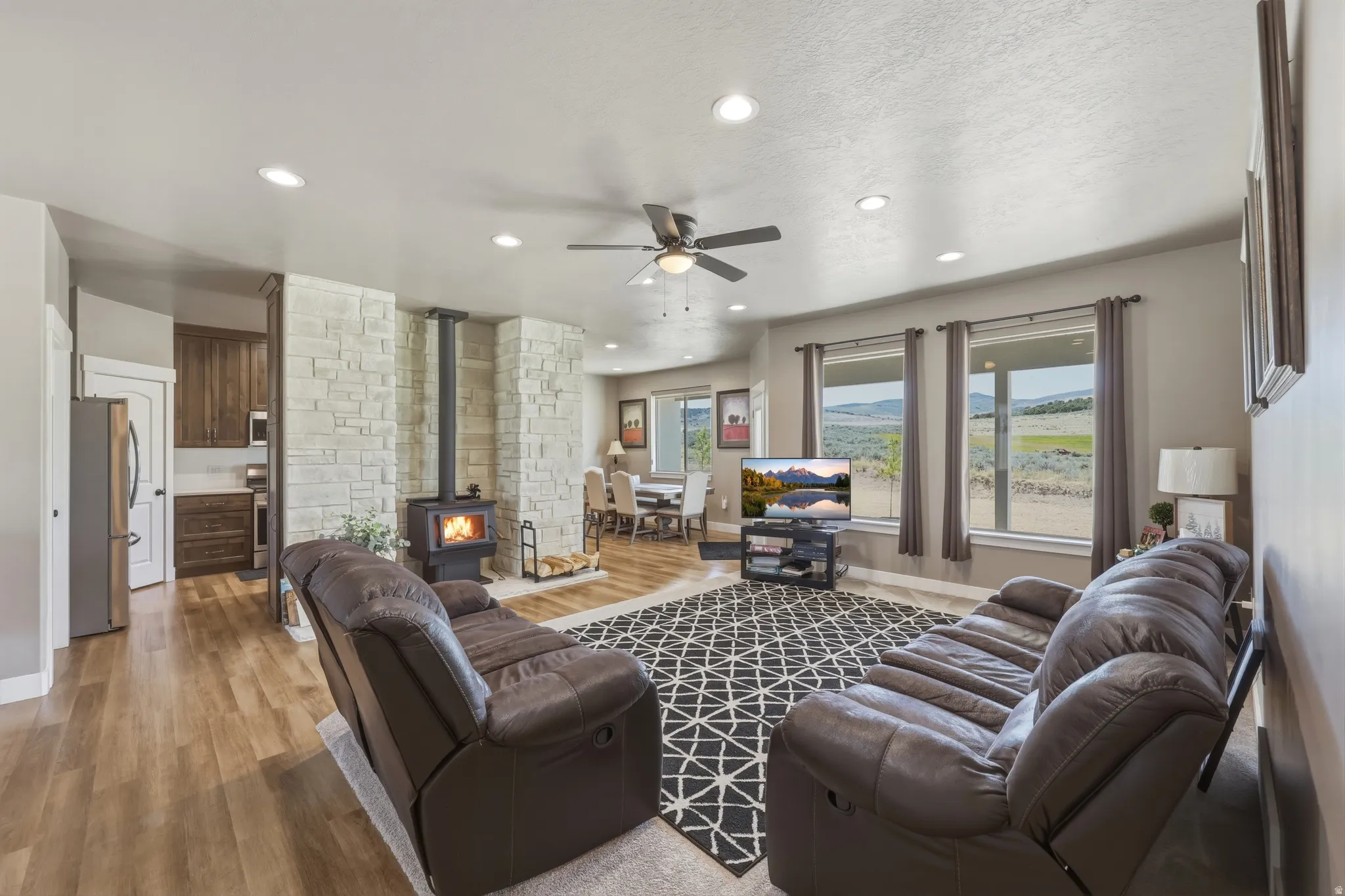 Open-concept living space featuring a wood-burning stove with a stone surround