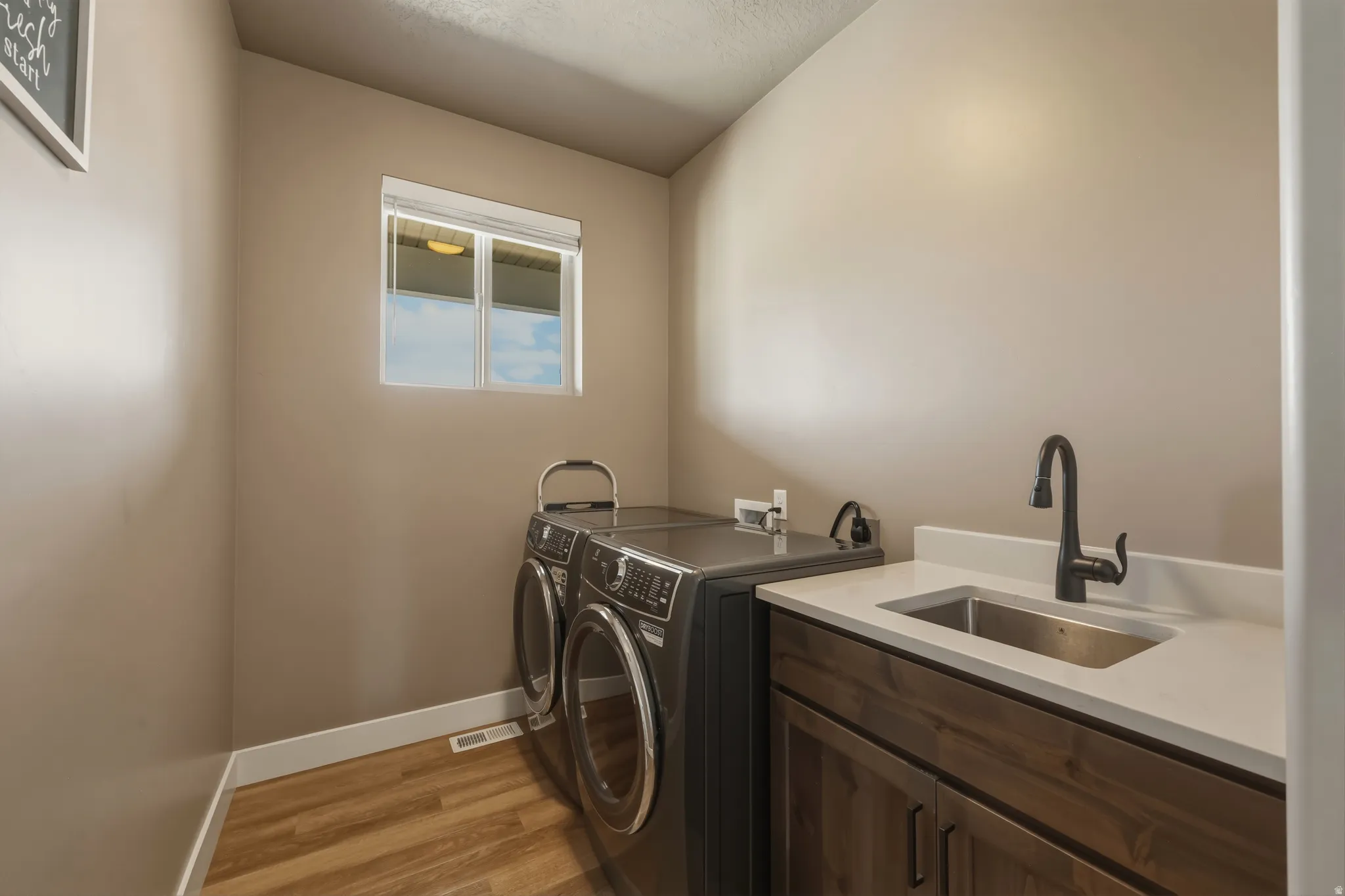 Utility room featuring wood-finish flooring and a window with blinds