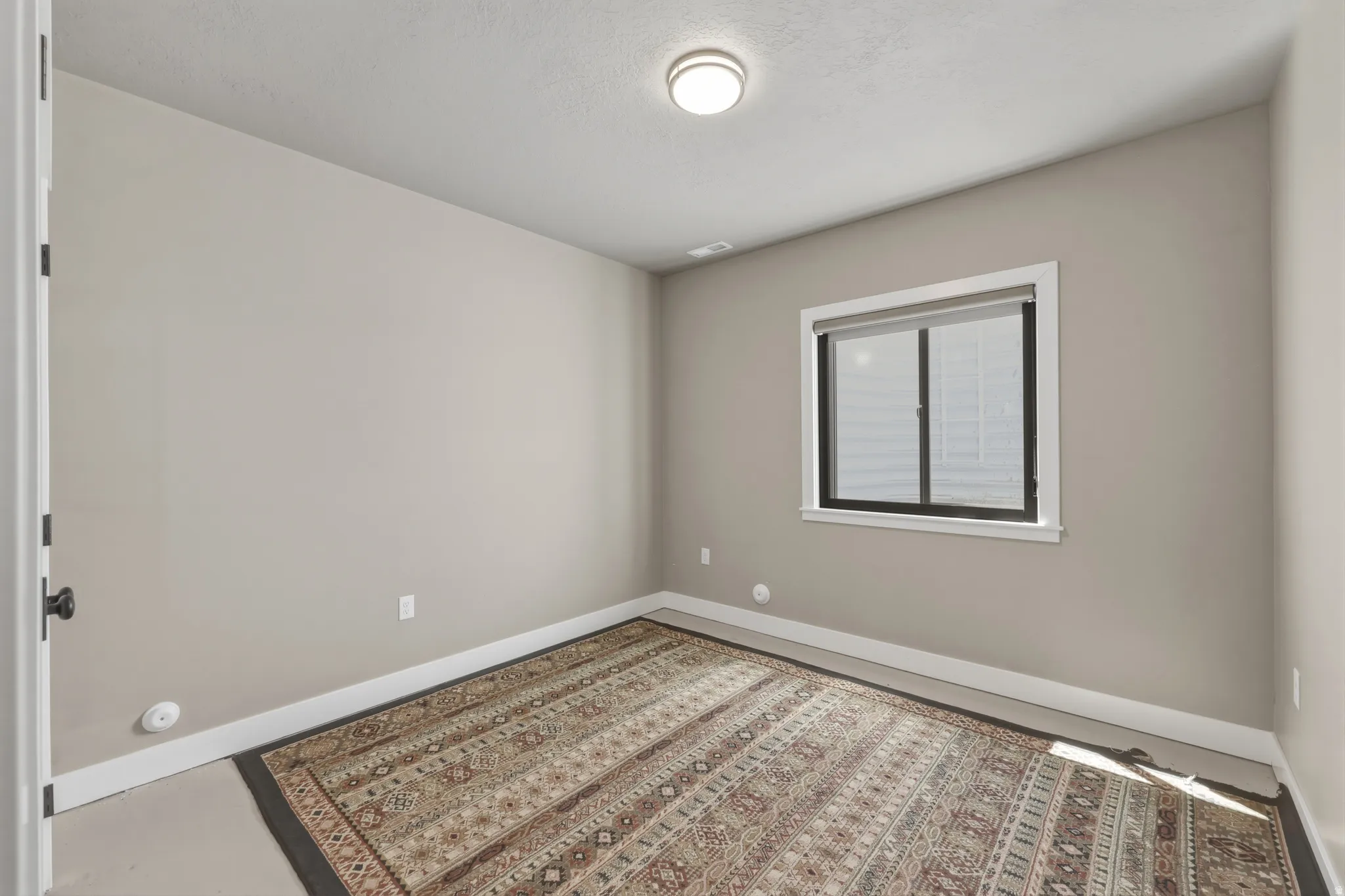 Neutral-toned interior with a single window featuring a roller shade