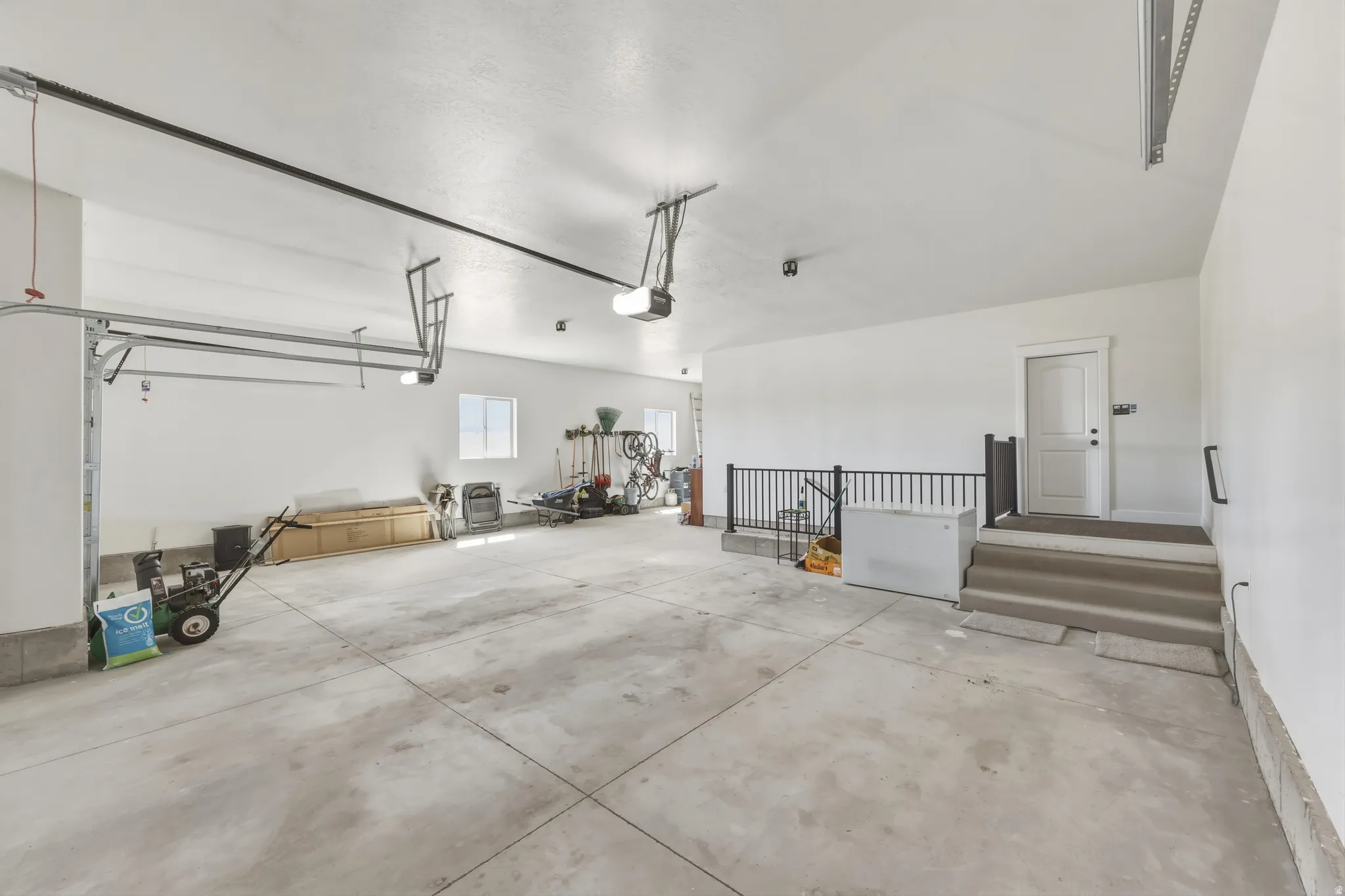 Spacious three-car garage featuring a concrete floor, white painted walls, and overhead lighting