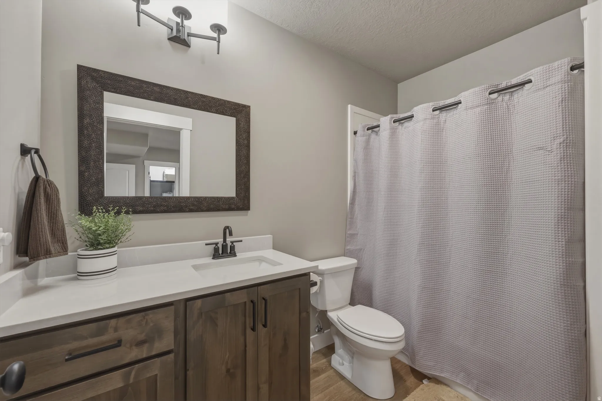 Bathroom featuring a wood-finish vanity with a white countertop, undermount sink, and matte black faucet