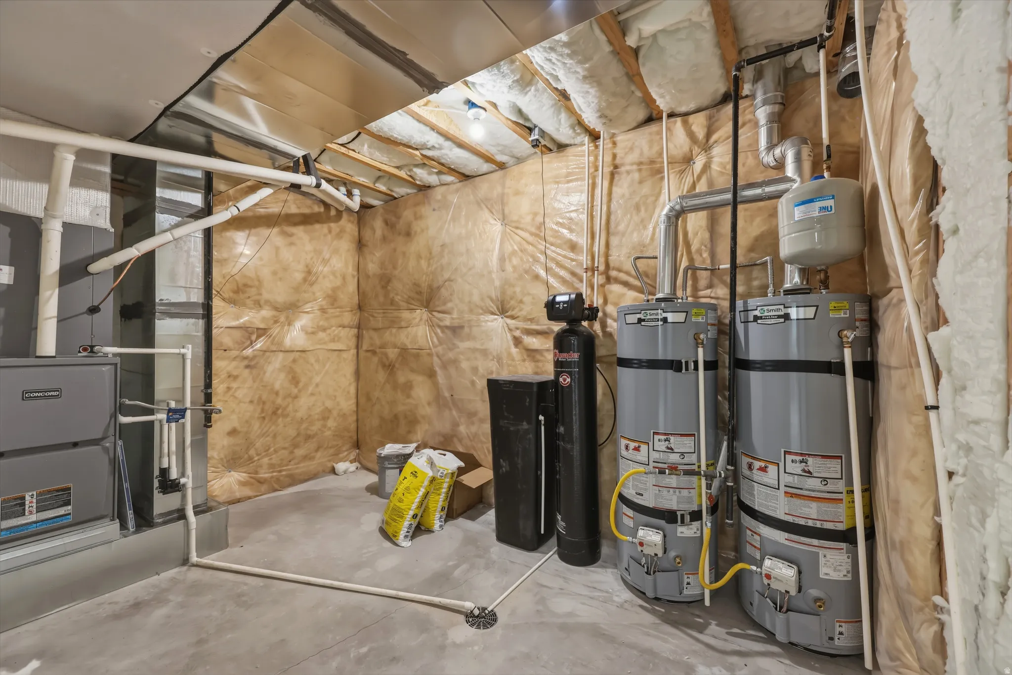 Utility area featuring dual hot water heaters, a water softener system, and exposed mechanicals