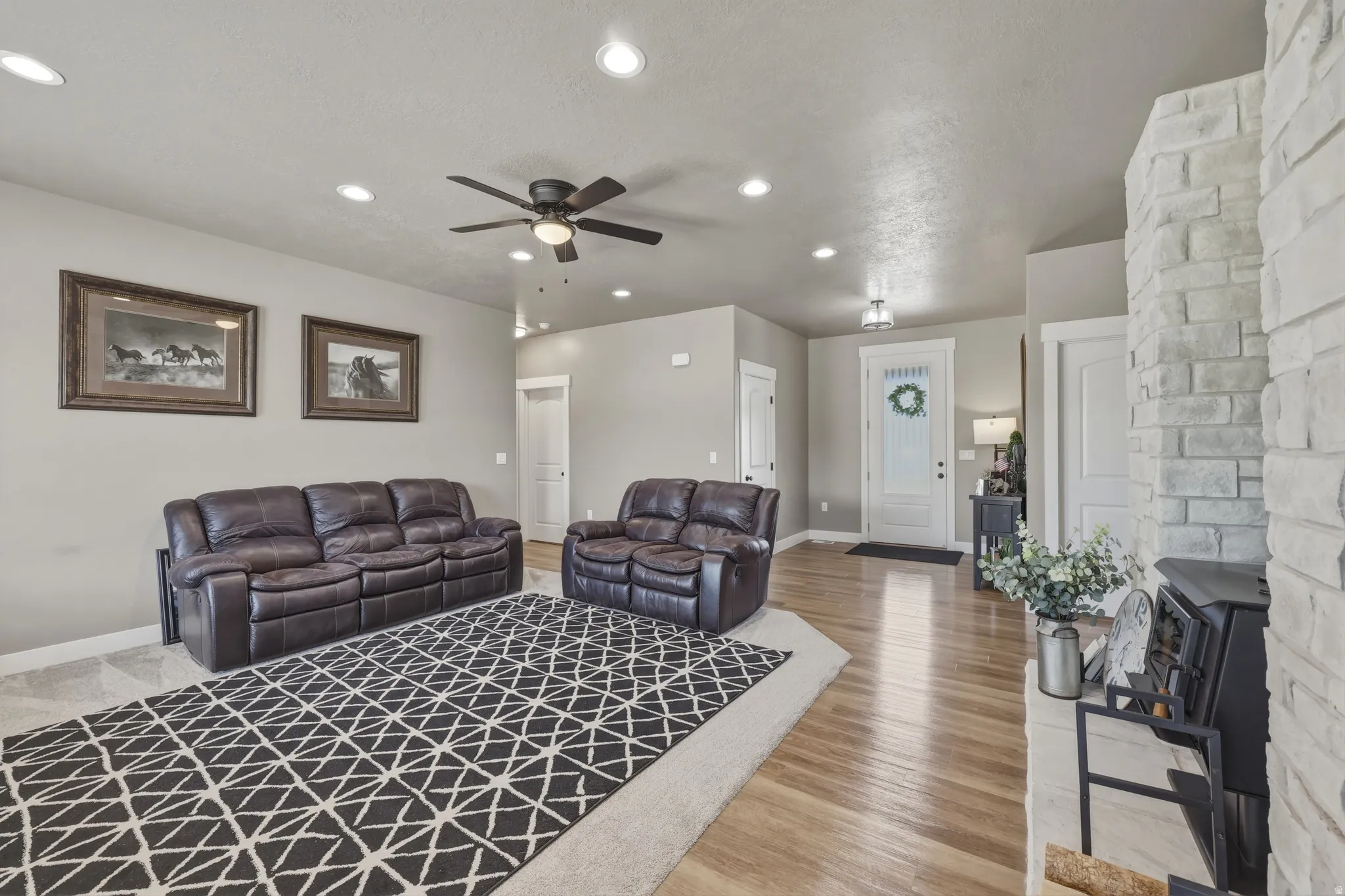 Living area featuring a stone-clad fireplace with a black wood-burning stove