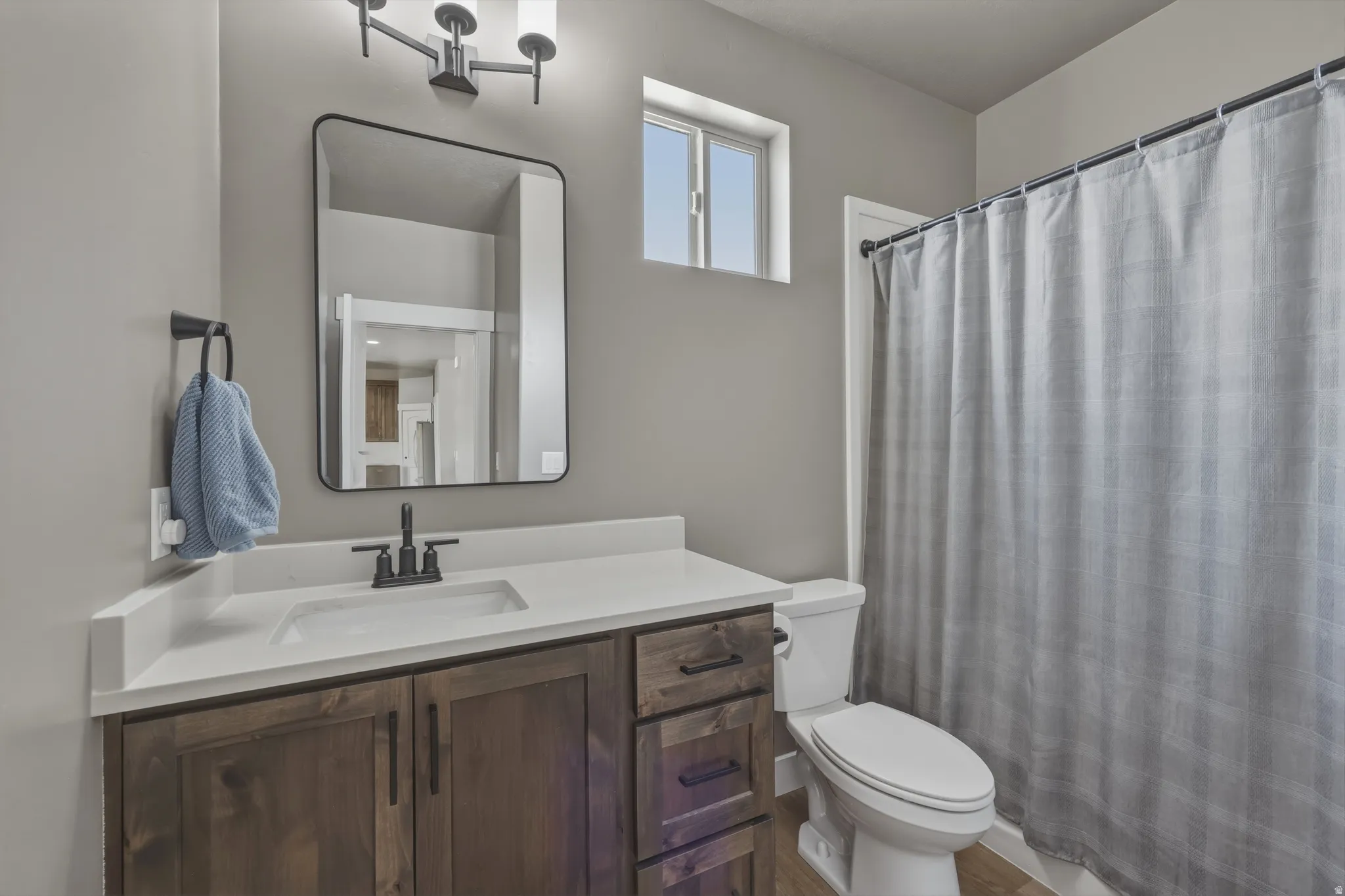 Contemporary bathroom featuring a dark wood-finish vanity with a white countertop and integrated sink