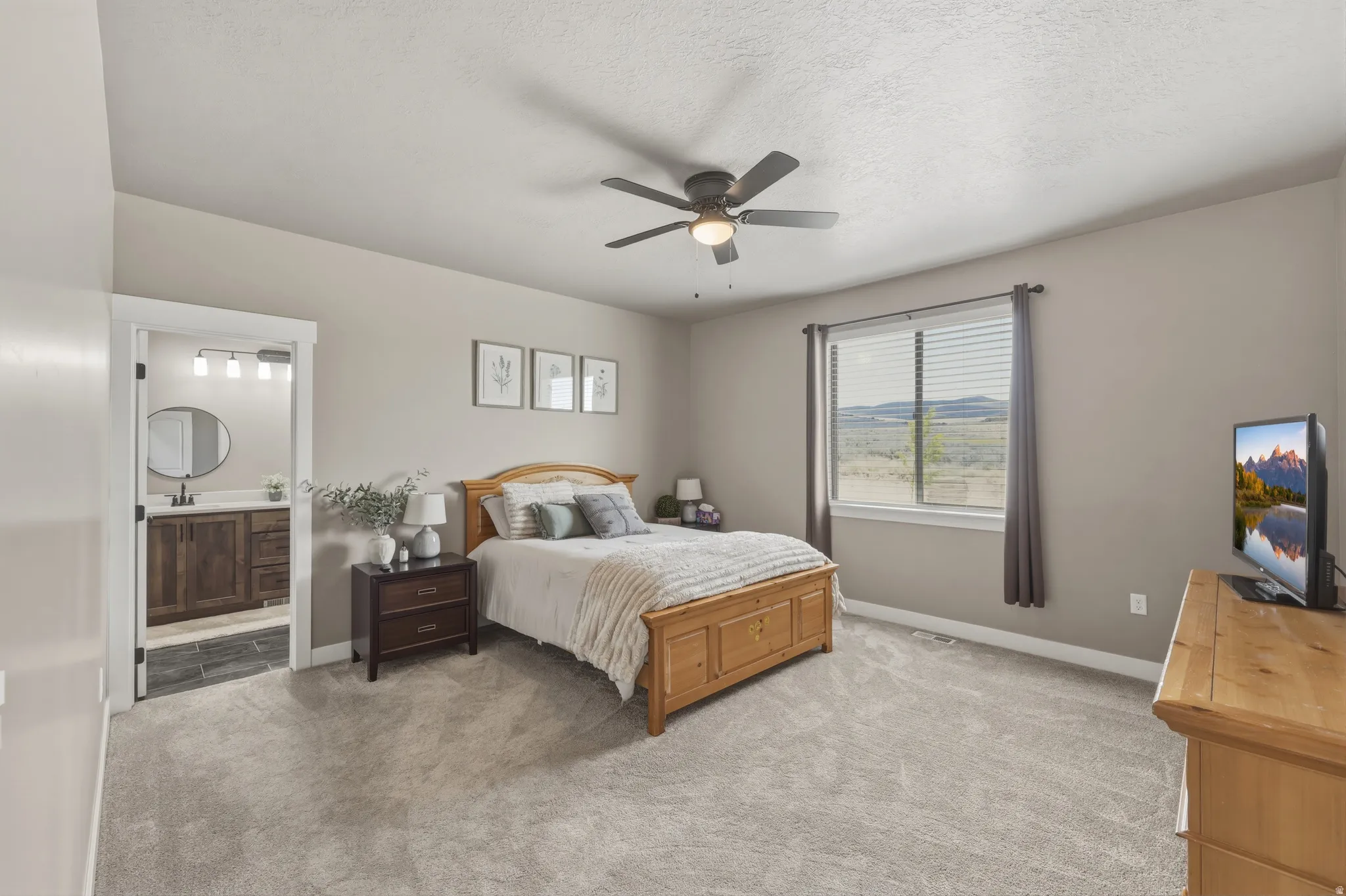 Carpeted bedroom featuring a ceiling fan, a window with horizontal blinds, and an open doorway to a bathroom