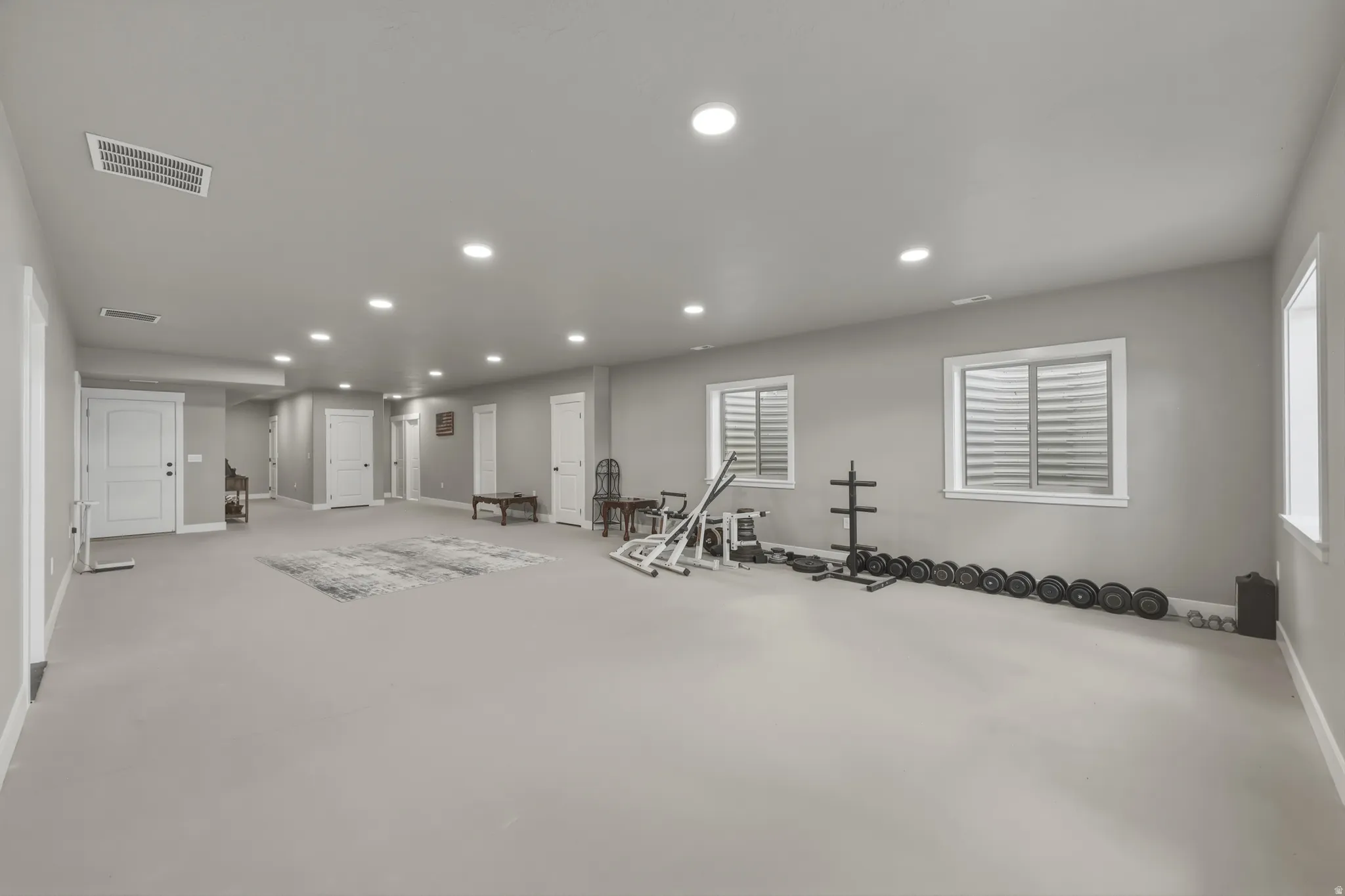 Spacious room featuring light gray walls, recessed lighting, and multiple windows with white trim