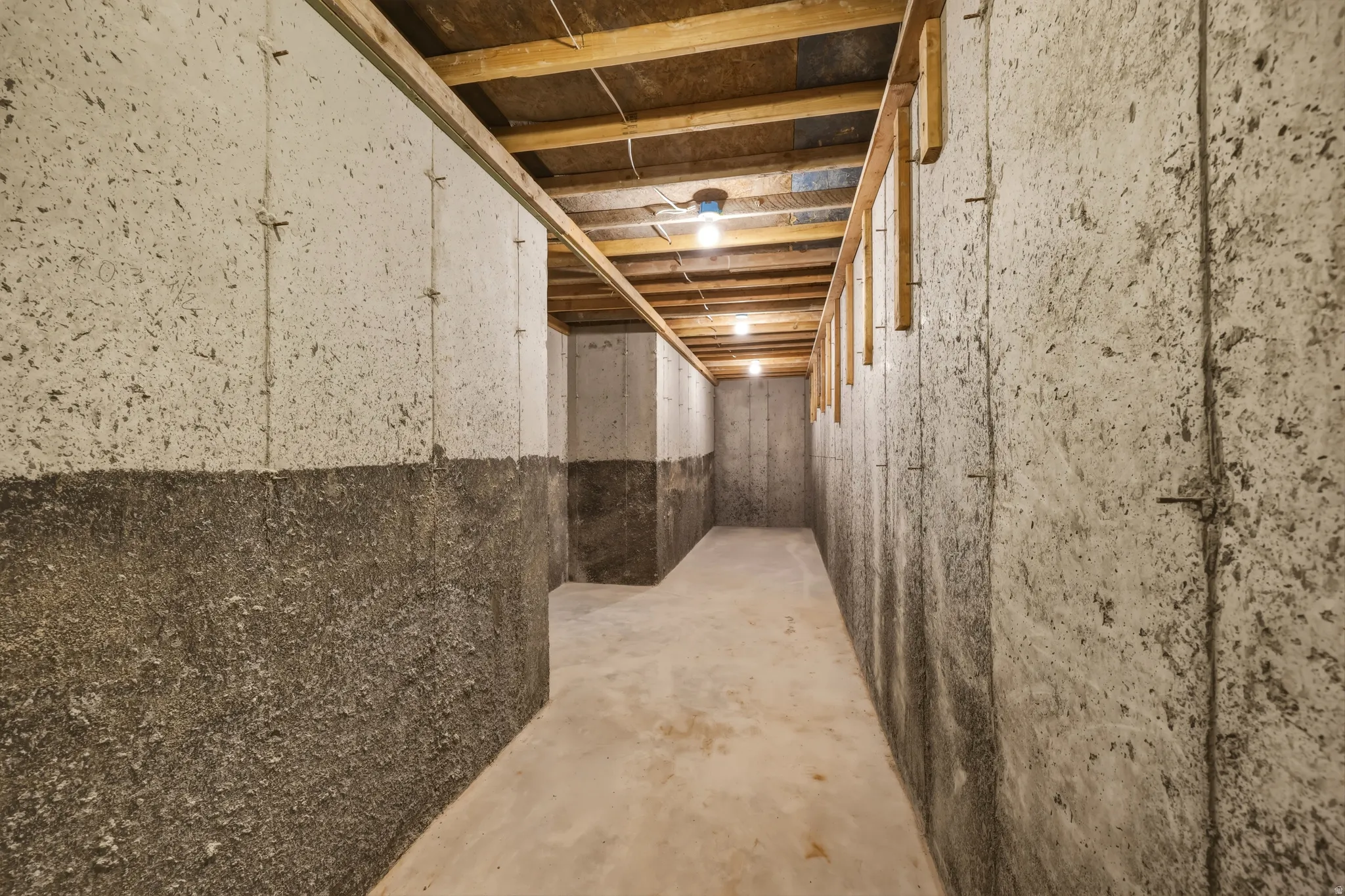 Unfinished basement featuring concrete walls, exposed ceiling joists, and concrete flooring