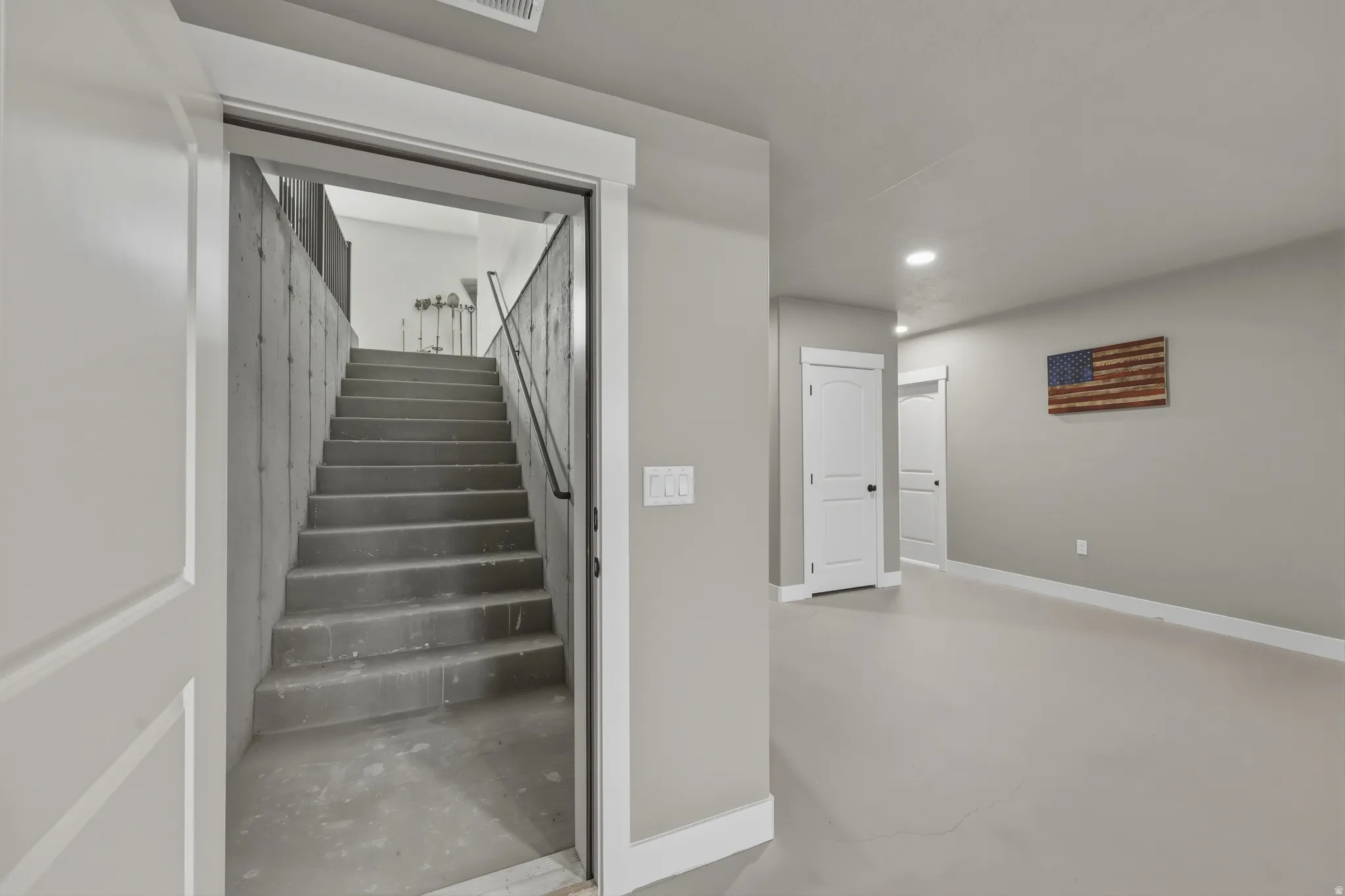 Concrete staircase with a black metal handrail providing access to the upper level