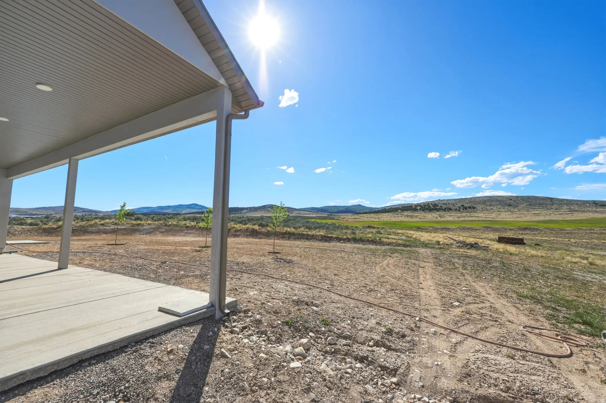 Covered concrete patio with recessed lighting, offering expansive land and distant mountain scenery