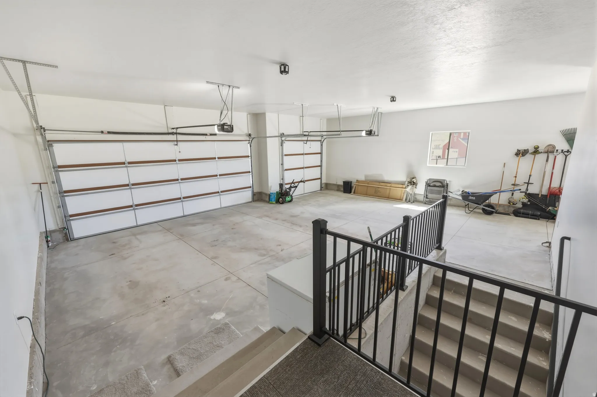 Spacious garage with light gray concrete flooring and two overhead garage doors
