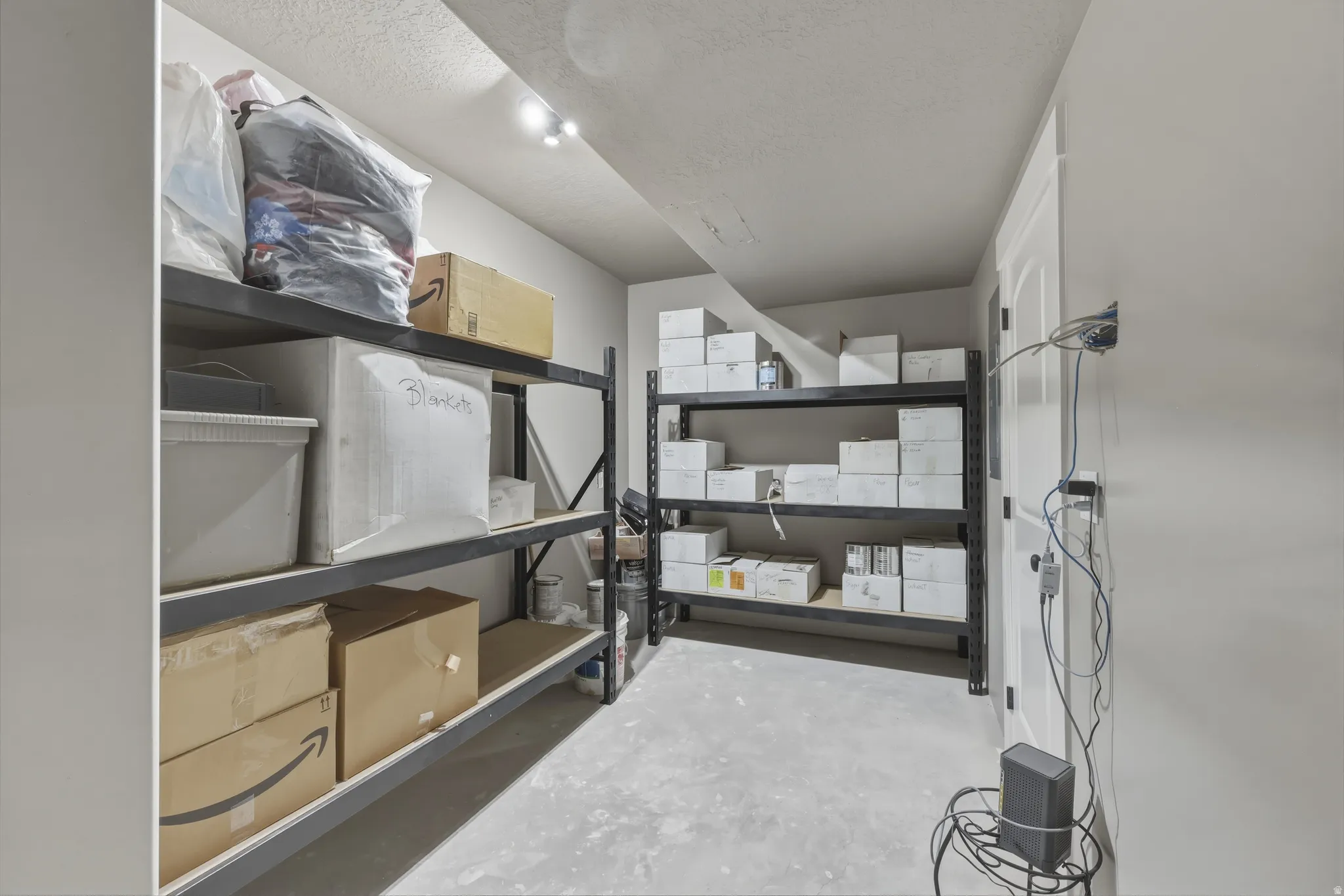 Utility room with concrete flooring, track lighting, and a white paneled door