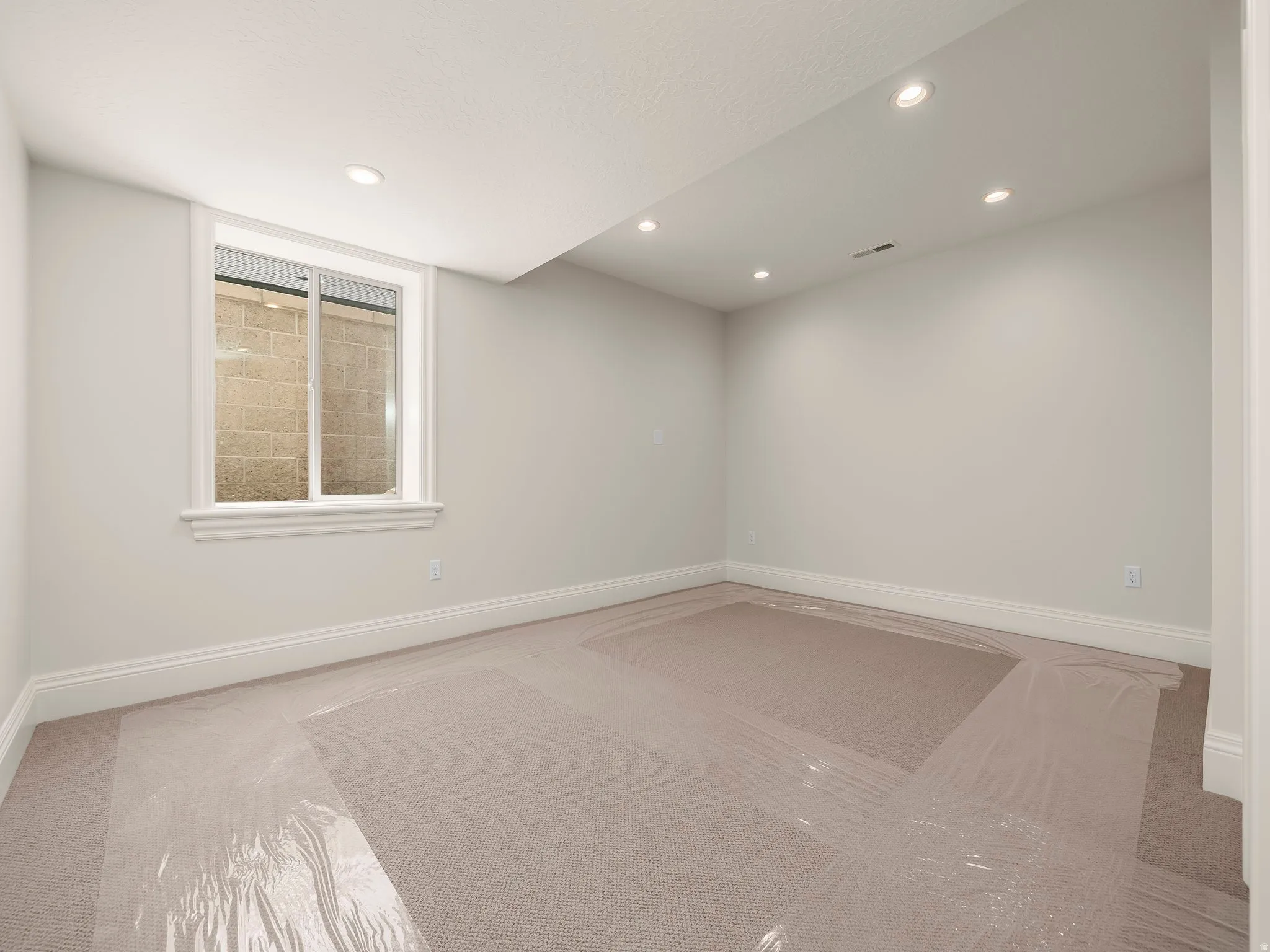 Neutral wall paint, recessed lighting, white baseboards, and a window with a white frame