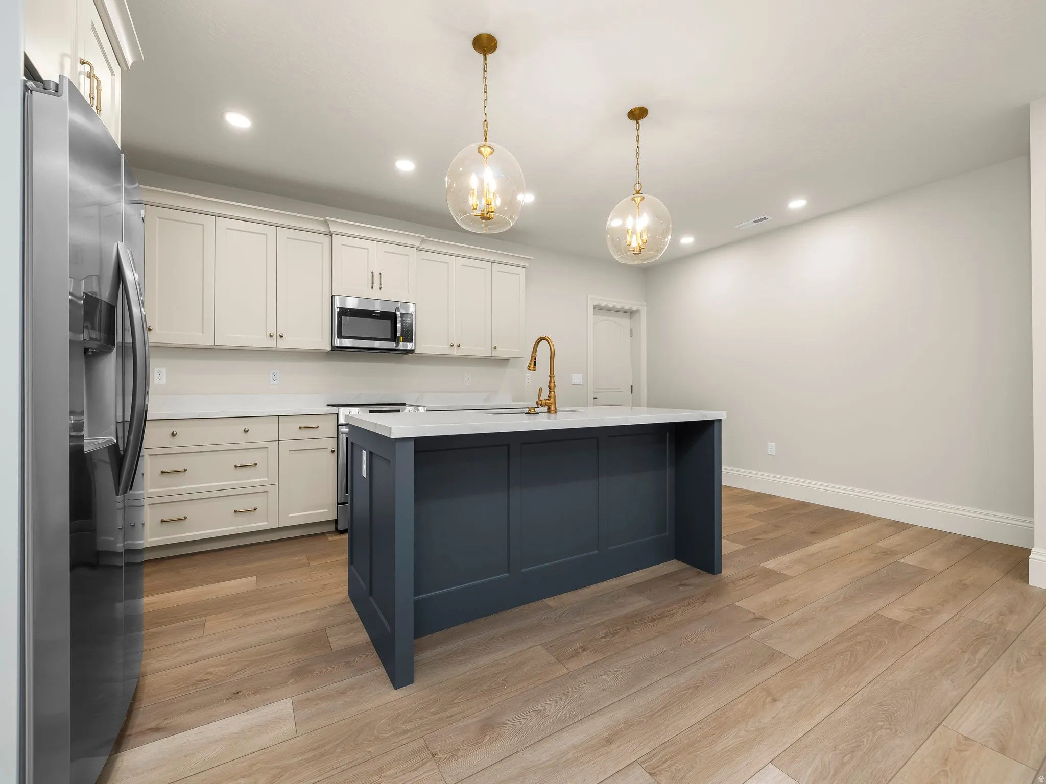 Modern kitchen featuring a contrasting island with a solid surface countertop and brass-finish faucet