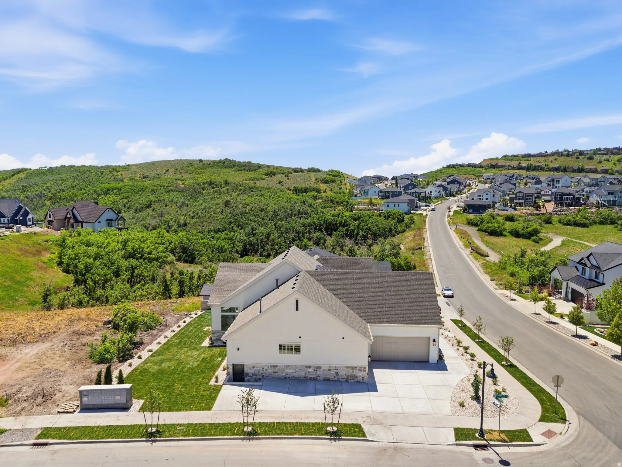 Contemporary residence featuring a light-toned exterior with stone accents, an attached two-car garage, and a concrete driveway