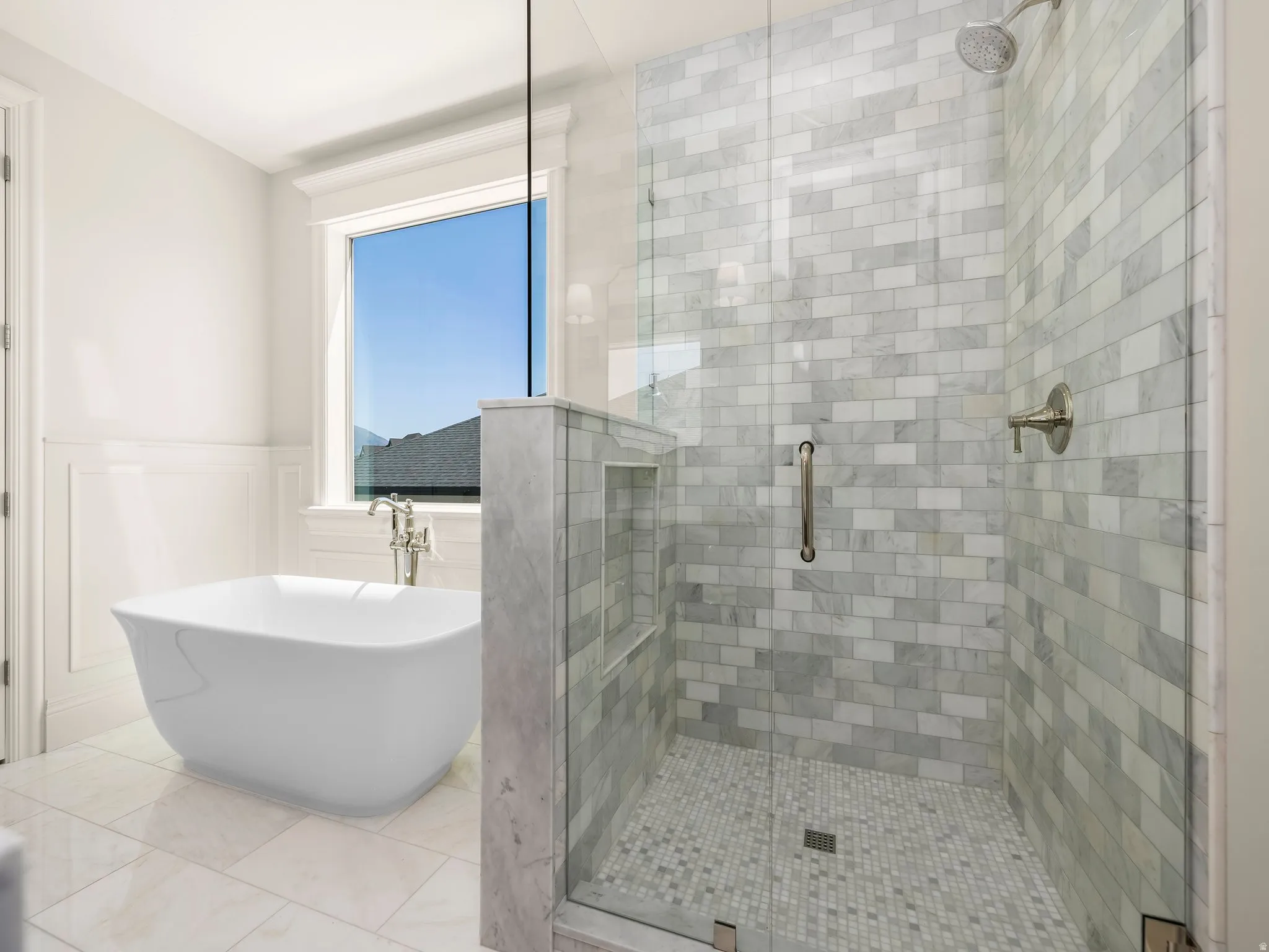 Glass-enclosed shower with subway tile walls and mosaic tile flooring