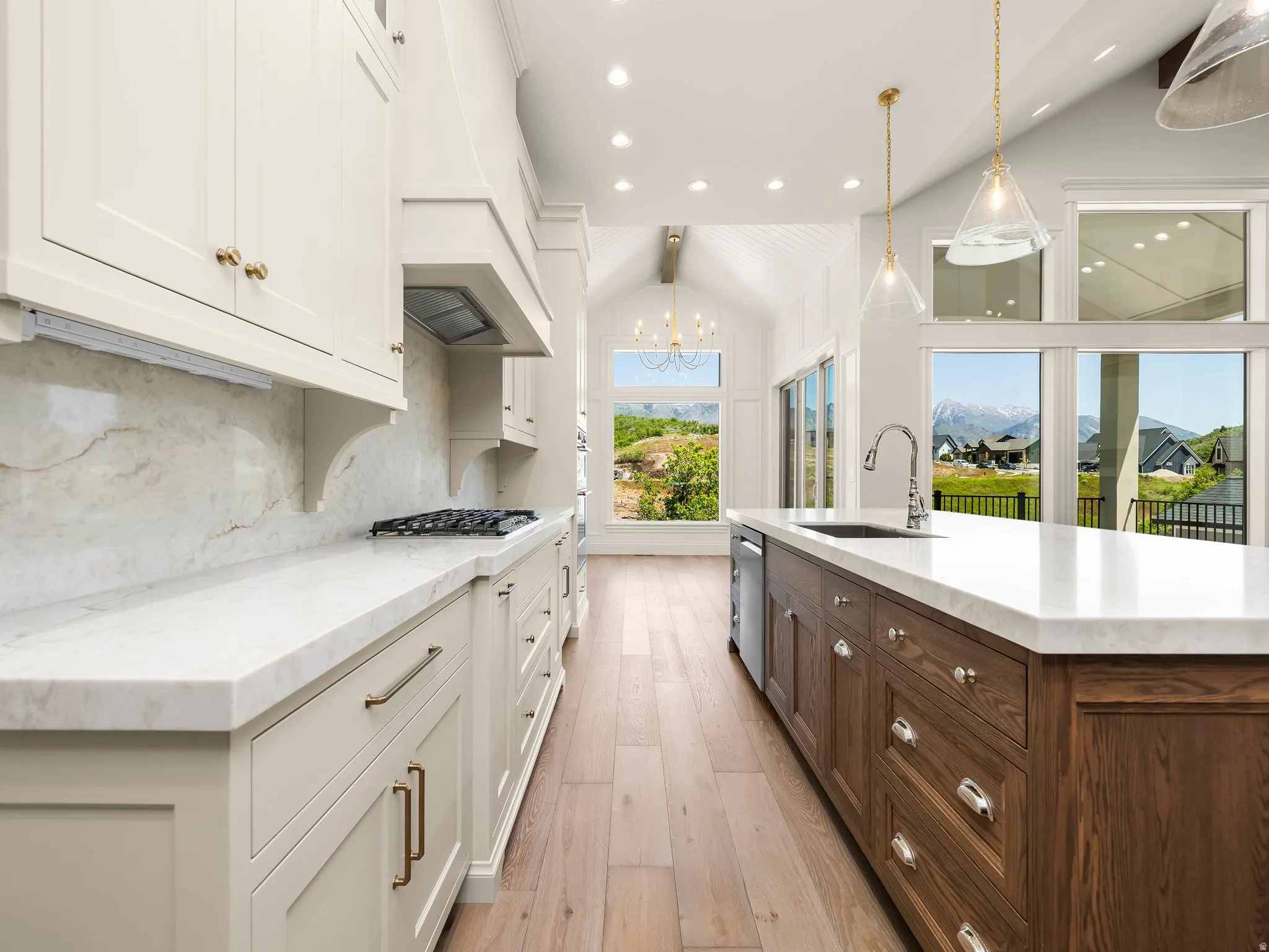 Spacious kitchen featuring an expansive island with a built-in sink and dishwasher, white countertops, and wood-finish flooring