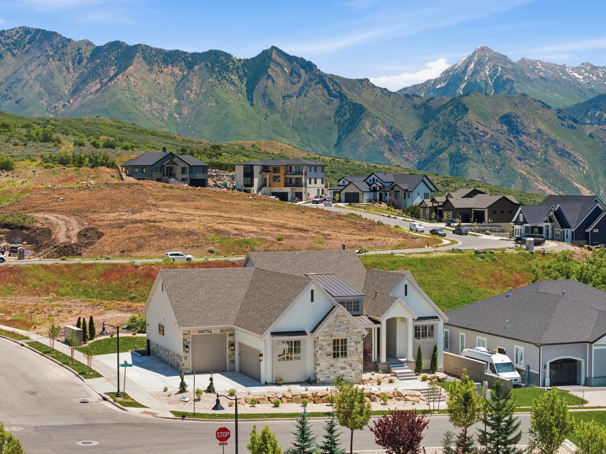 Contemporary residence featuring a light-colored exterior with stone accents, multiple gables, and a two-car garage