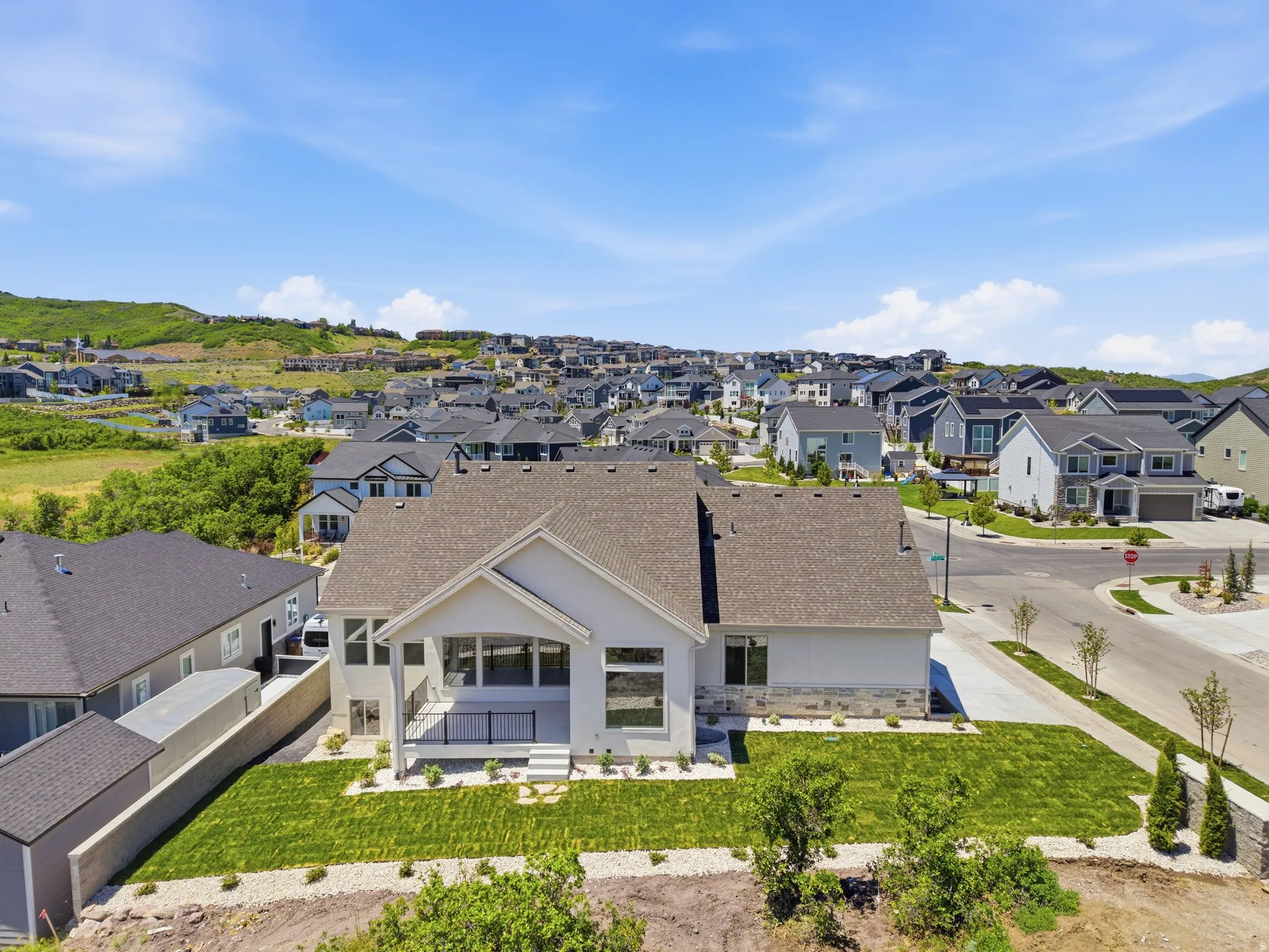 Contemporary residence featuring a light-toned exterior, dark shingle roof, and stone accents