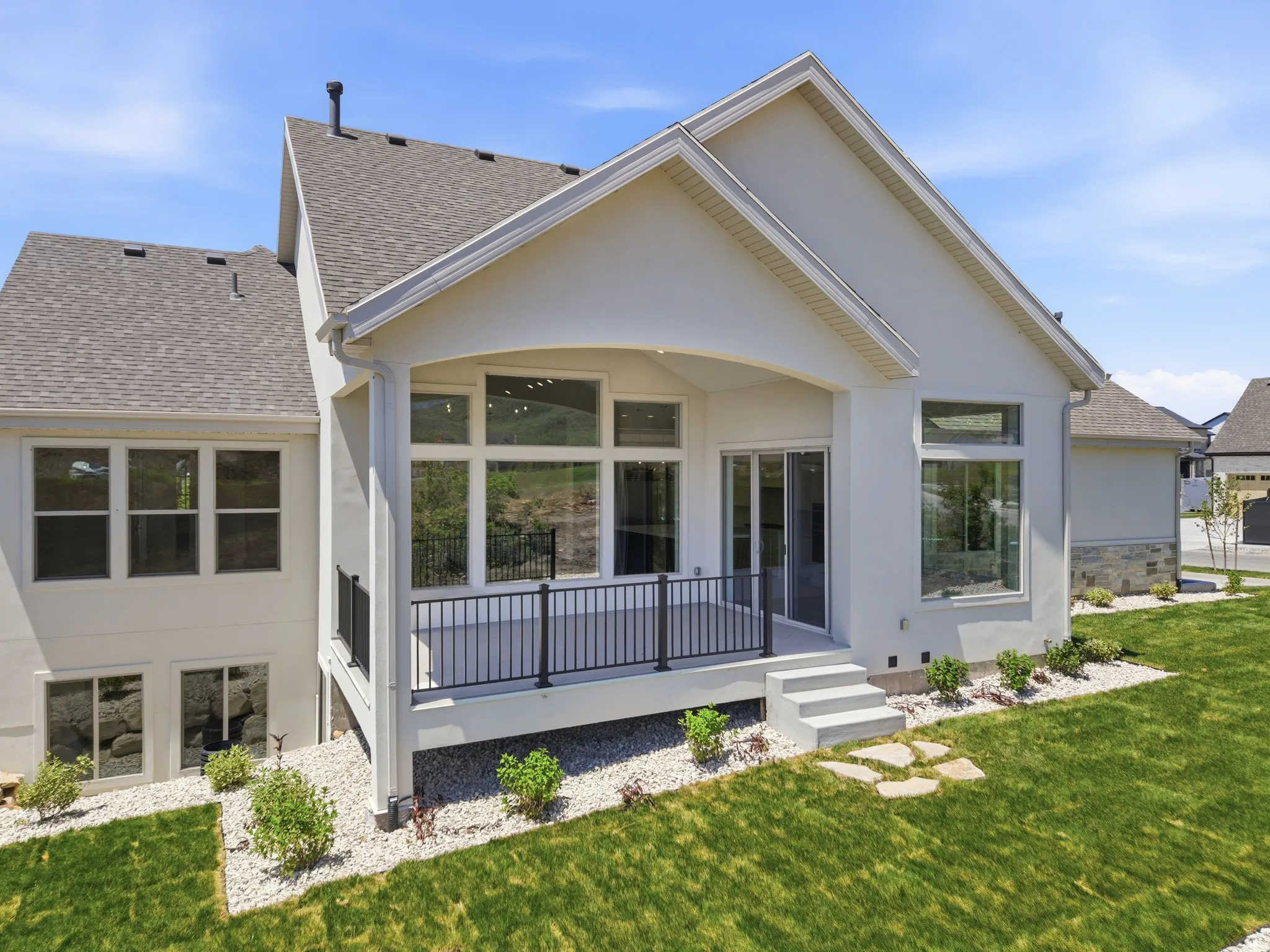 Contemporary stucco exterior with a covered balcony featuring a black metal railing
