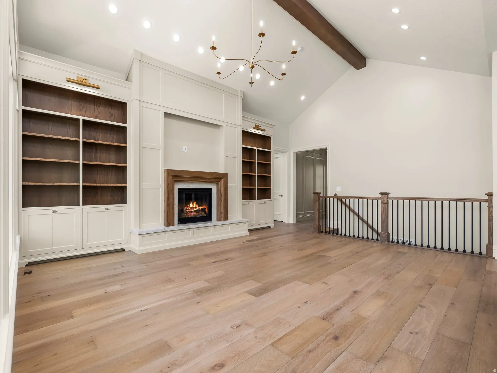 Great room with vaulted ceiling featuring a dark wood beam and a contemporary chandelier