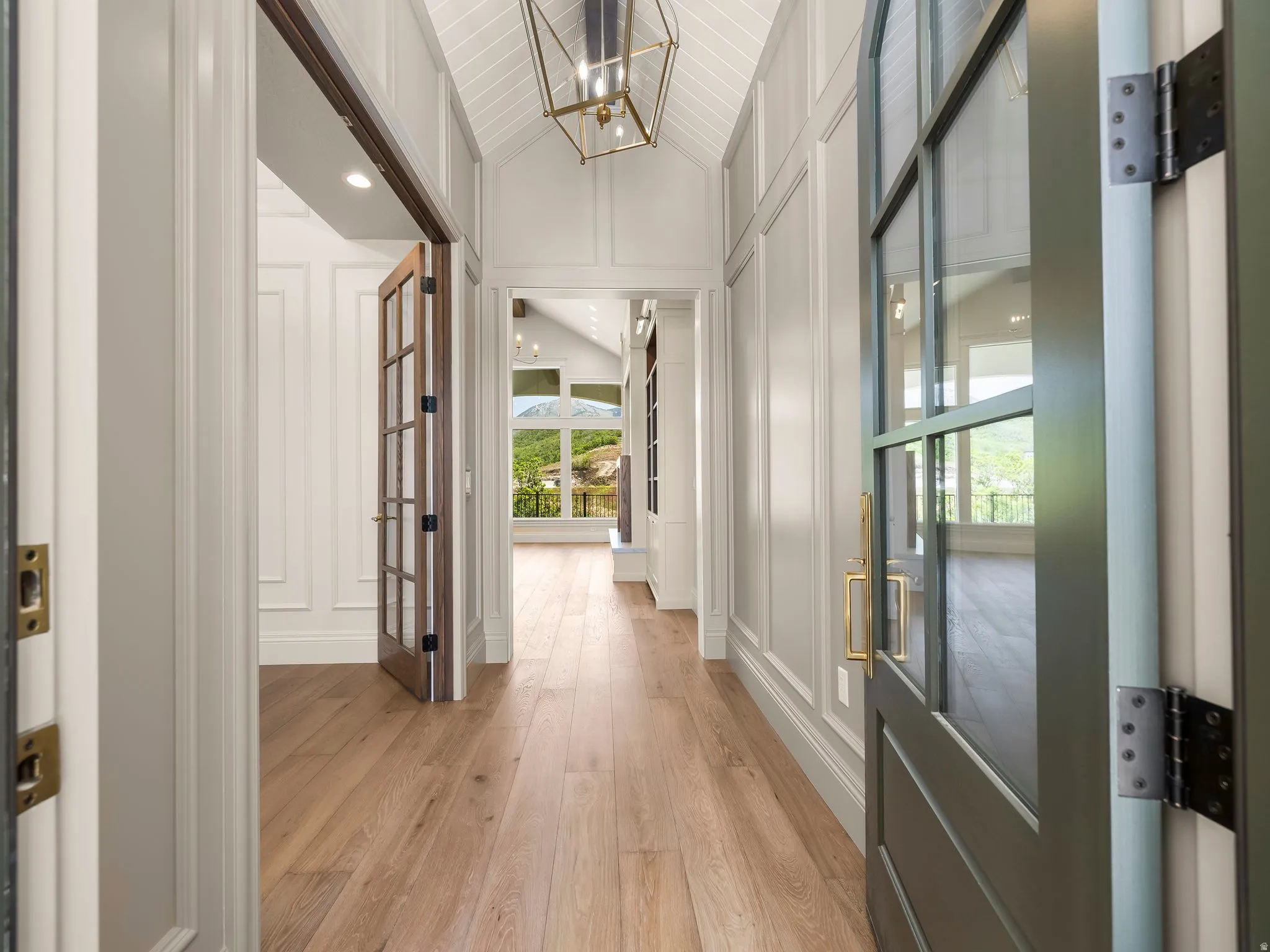 Entryway featuring wood-finish flooring, paneled walls, and a vaulted ceiling with a decorative light fixture