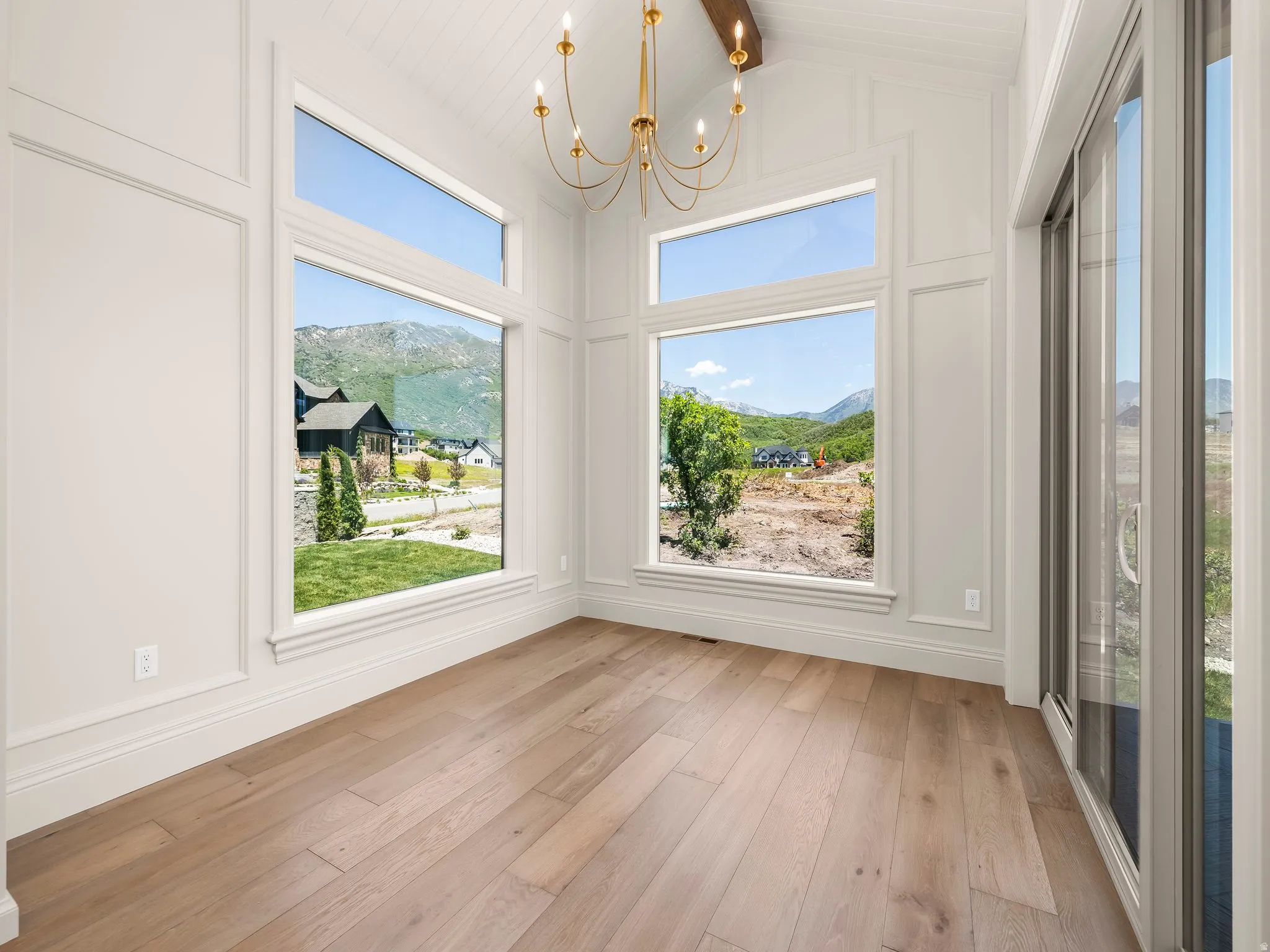 Vaulted ceiling featuring a brass chandelier with exposed wood beam