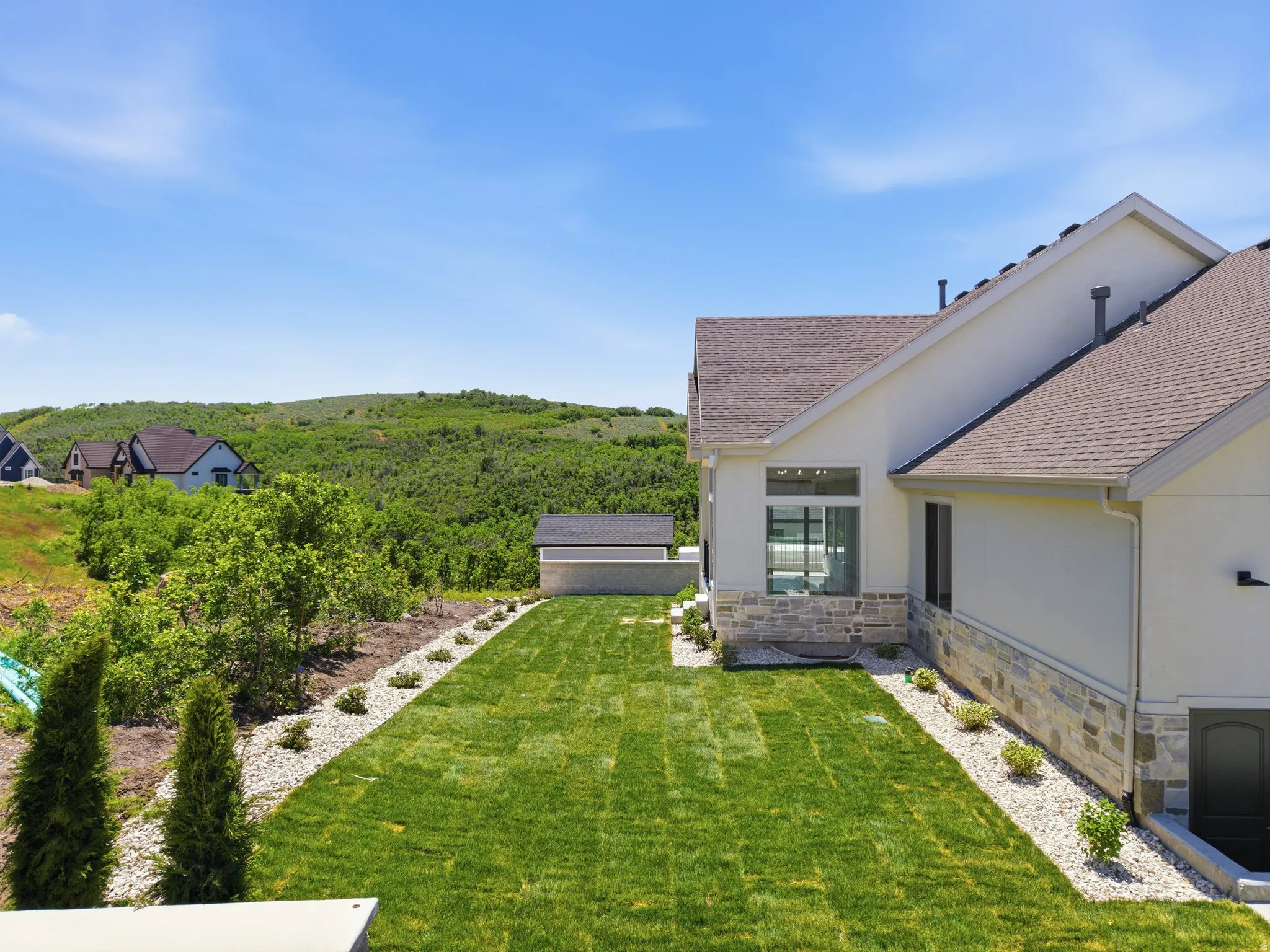 Expansive green lawn with a rock border and established plantings