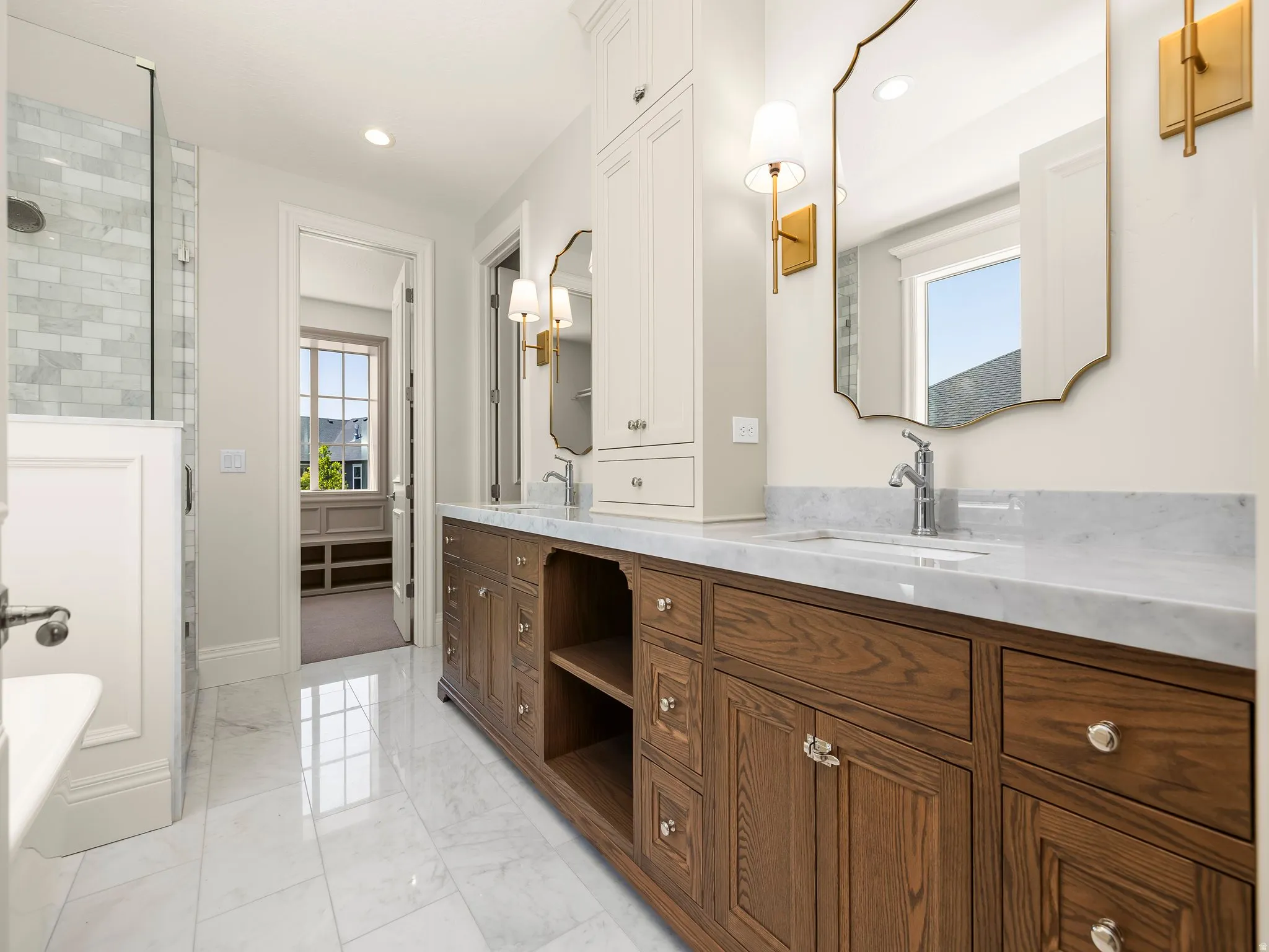 Spacious bathroom featuring a dual vanity with wood cabinetry and light-toned countertops, a glass-enclosed shower with subway tile, and polished tile flooring