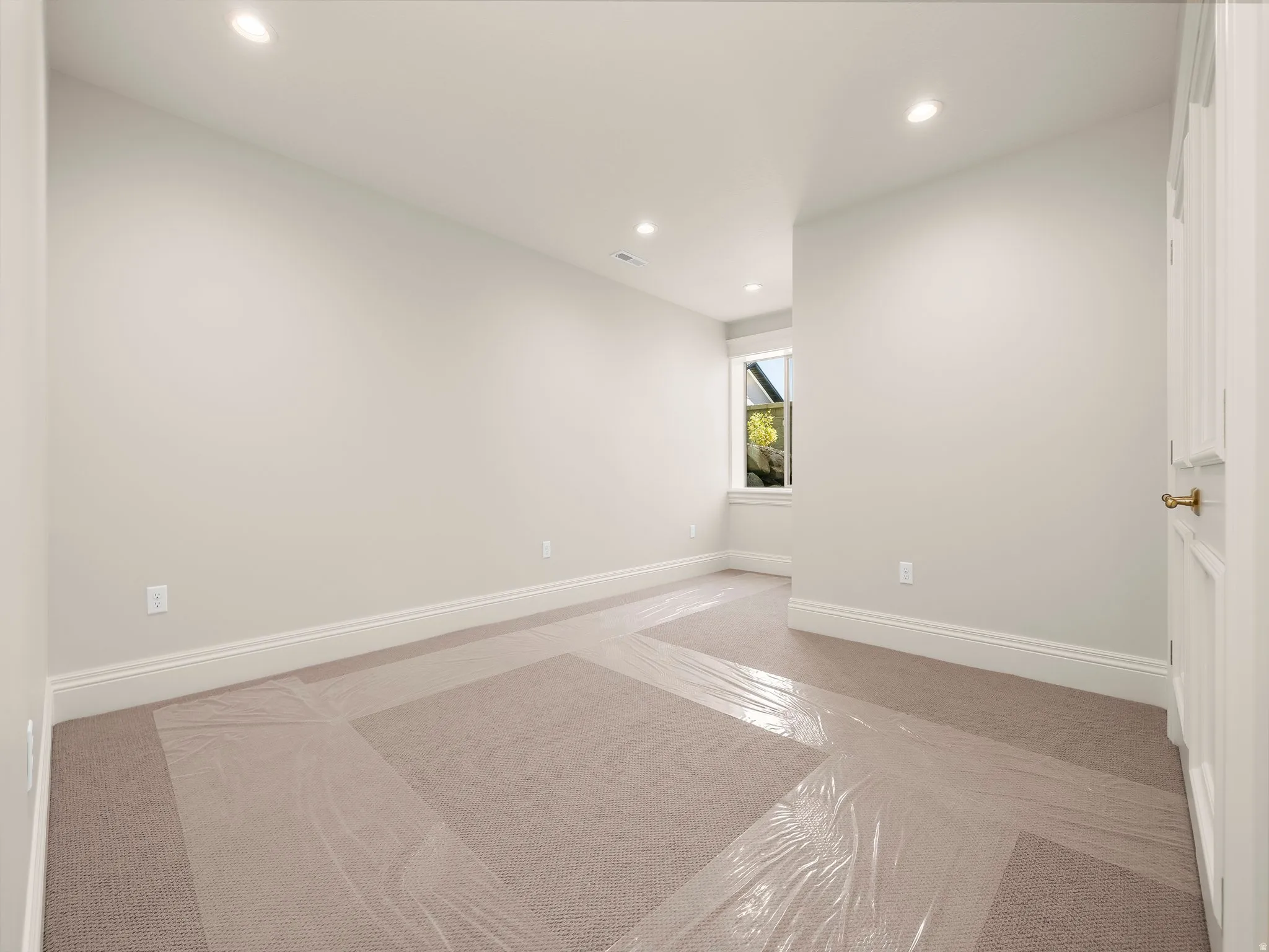 Interior room featuring recessed lighting, a single window, light beige wall paint, white trim, and light brown carpet