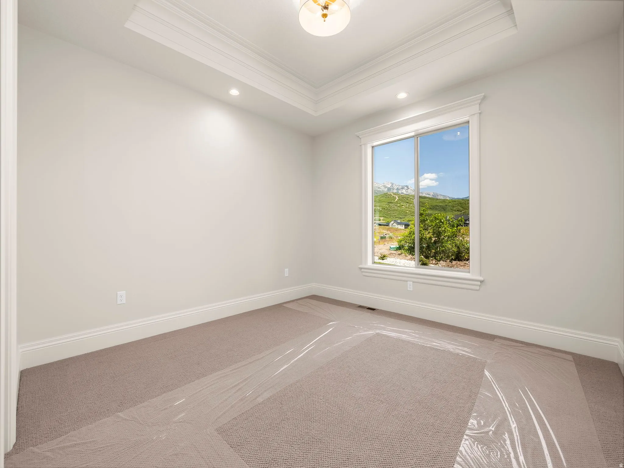 Neutral-toned room with a large window framing a distant mountainous landscape