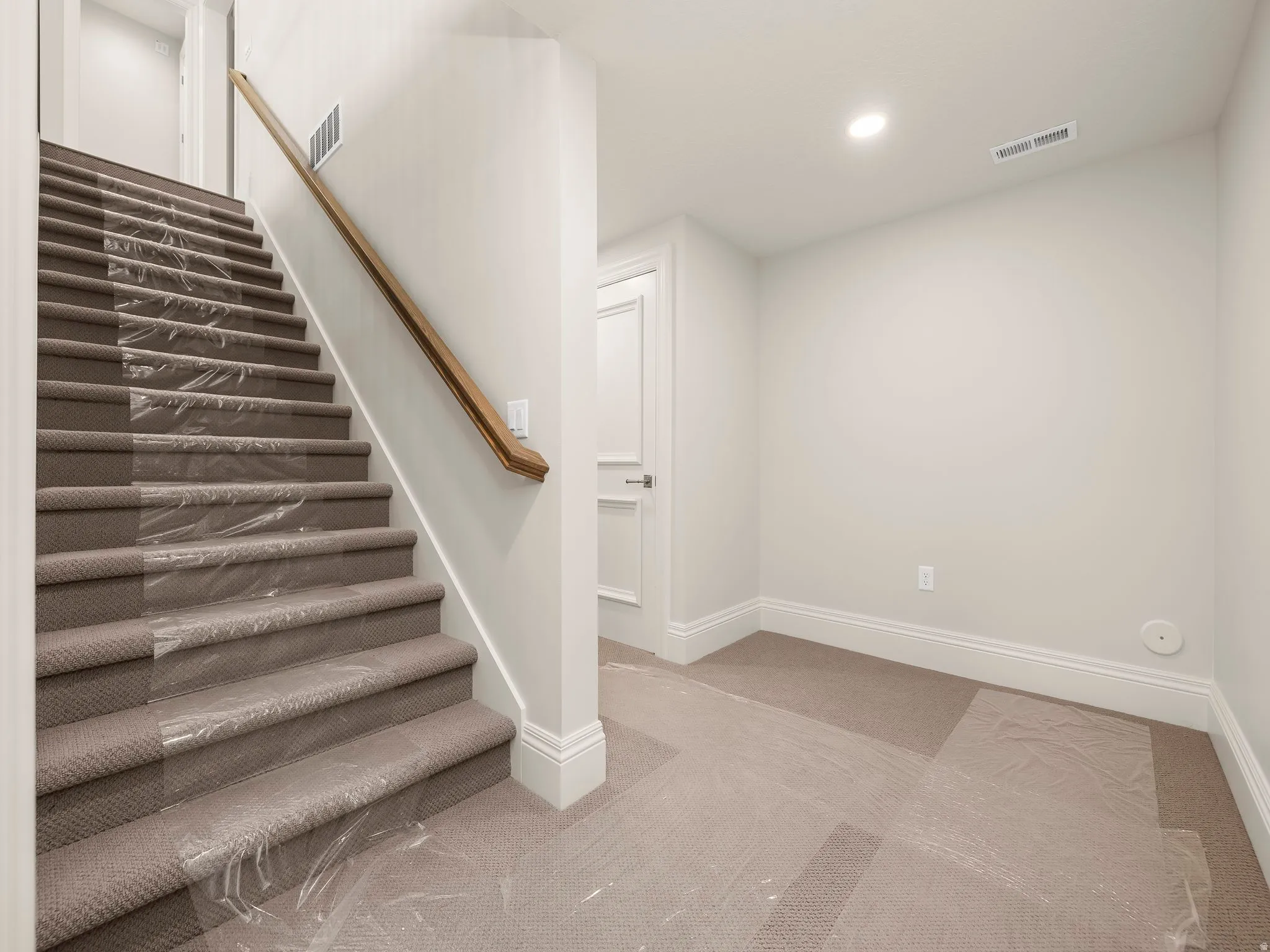 Carpeted staircase with a wood handrail