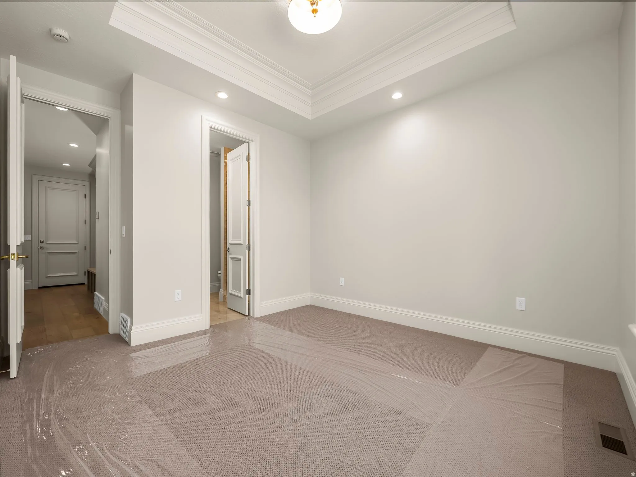Room featuring a tray ceiling with crown molding, recessed lighting, and a central ceiling fixture